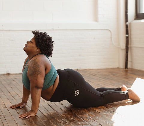 woman doing an upward dog pose in yoga wear by SuperFit Hero