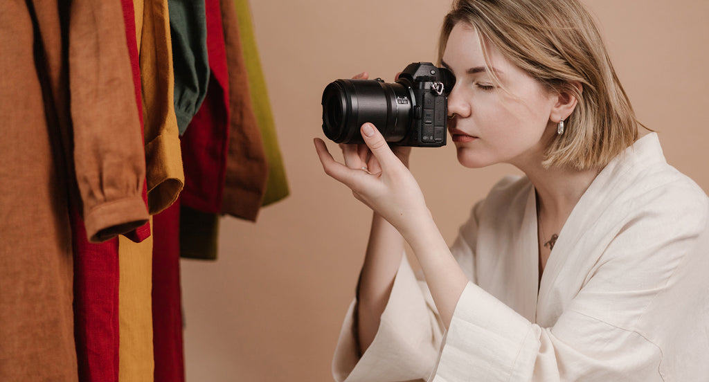 woman in white photographing clothing in a nude coloured studio 