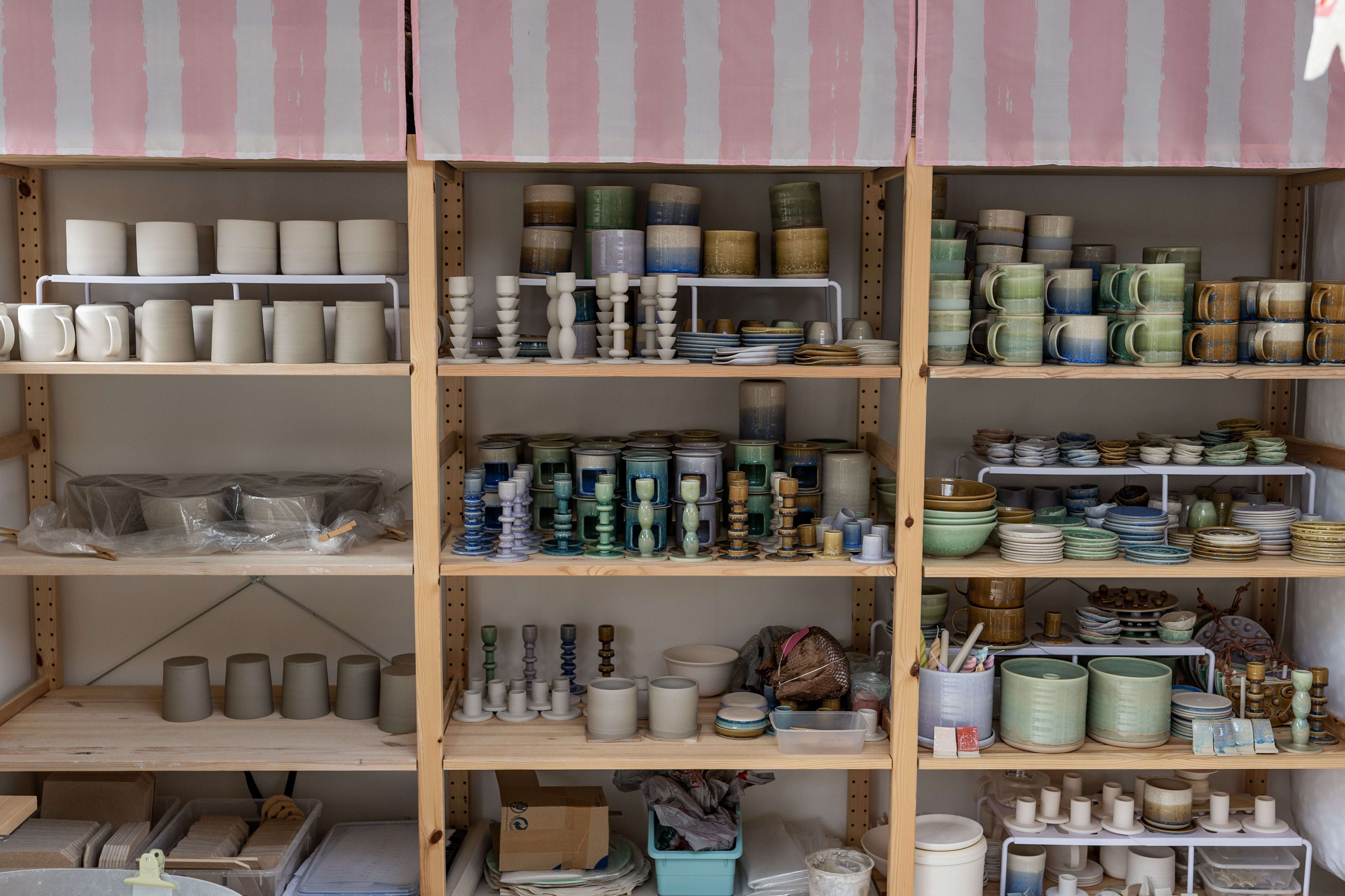 Shelves within the Glaze Me Pretty pottery studio filled with various ceramic pieces made by Raquel Acosta. 