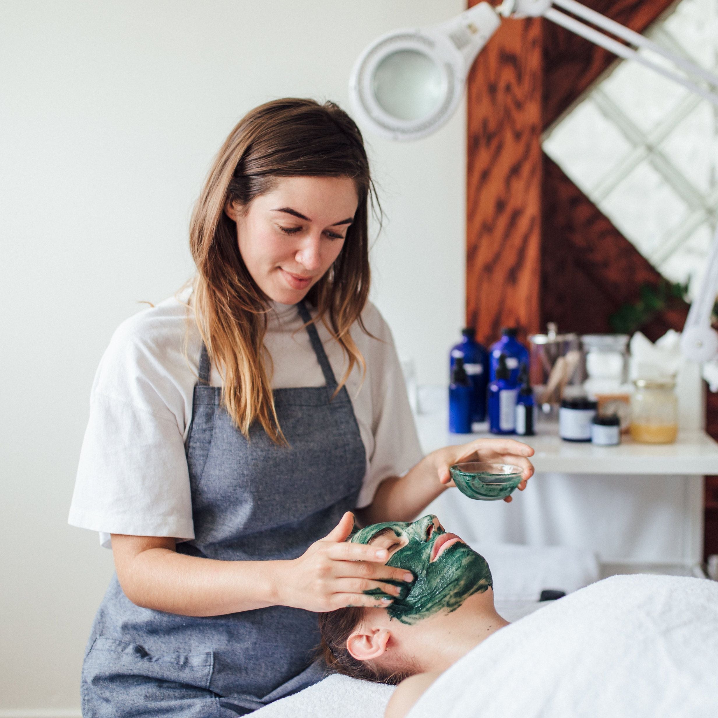 An aesthetician applying a face mask onto a client at Province Apothecary's retail location.  