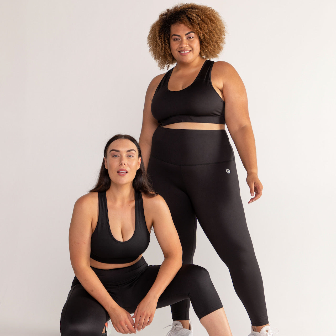 A pair of models in black workout sets by Active Truth against a white background. 