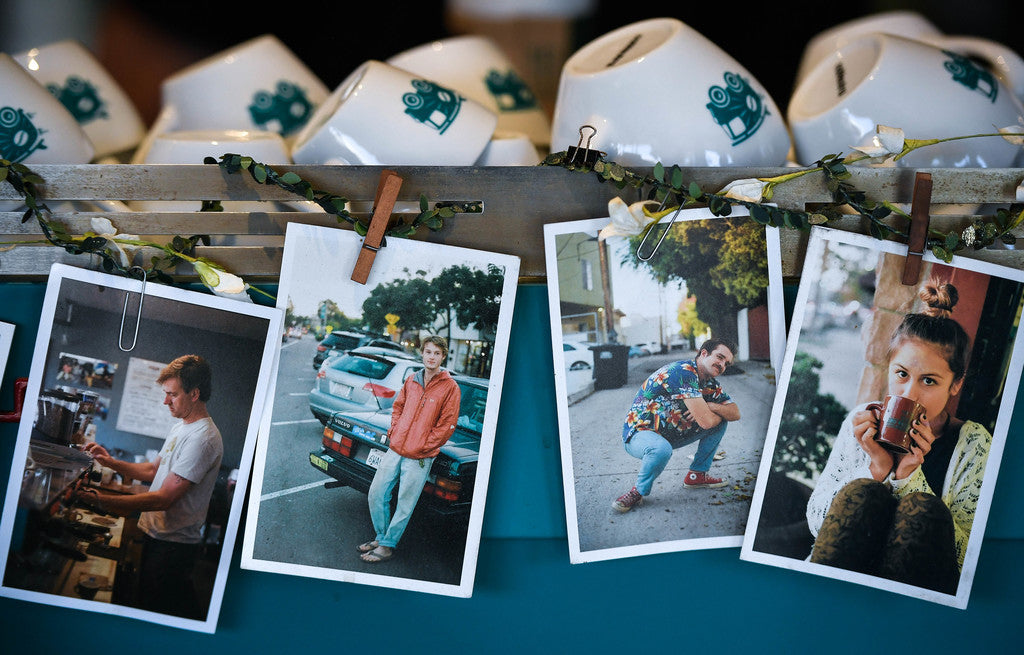 A row of employee photos lines a commercial coffee machine