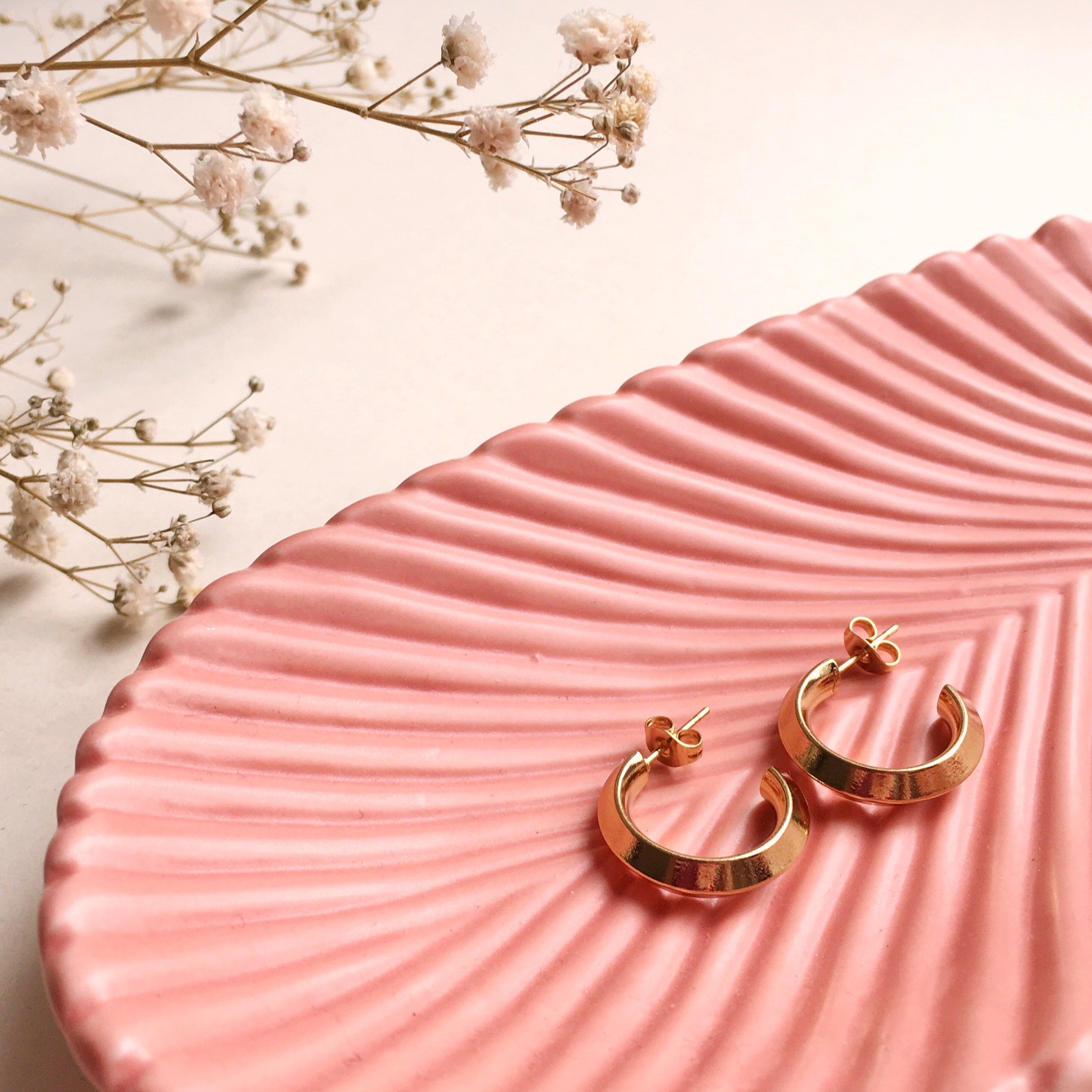 A pair of earrings sitting in a peach dish. 