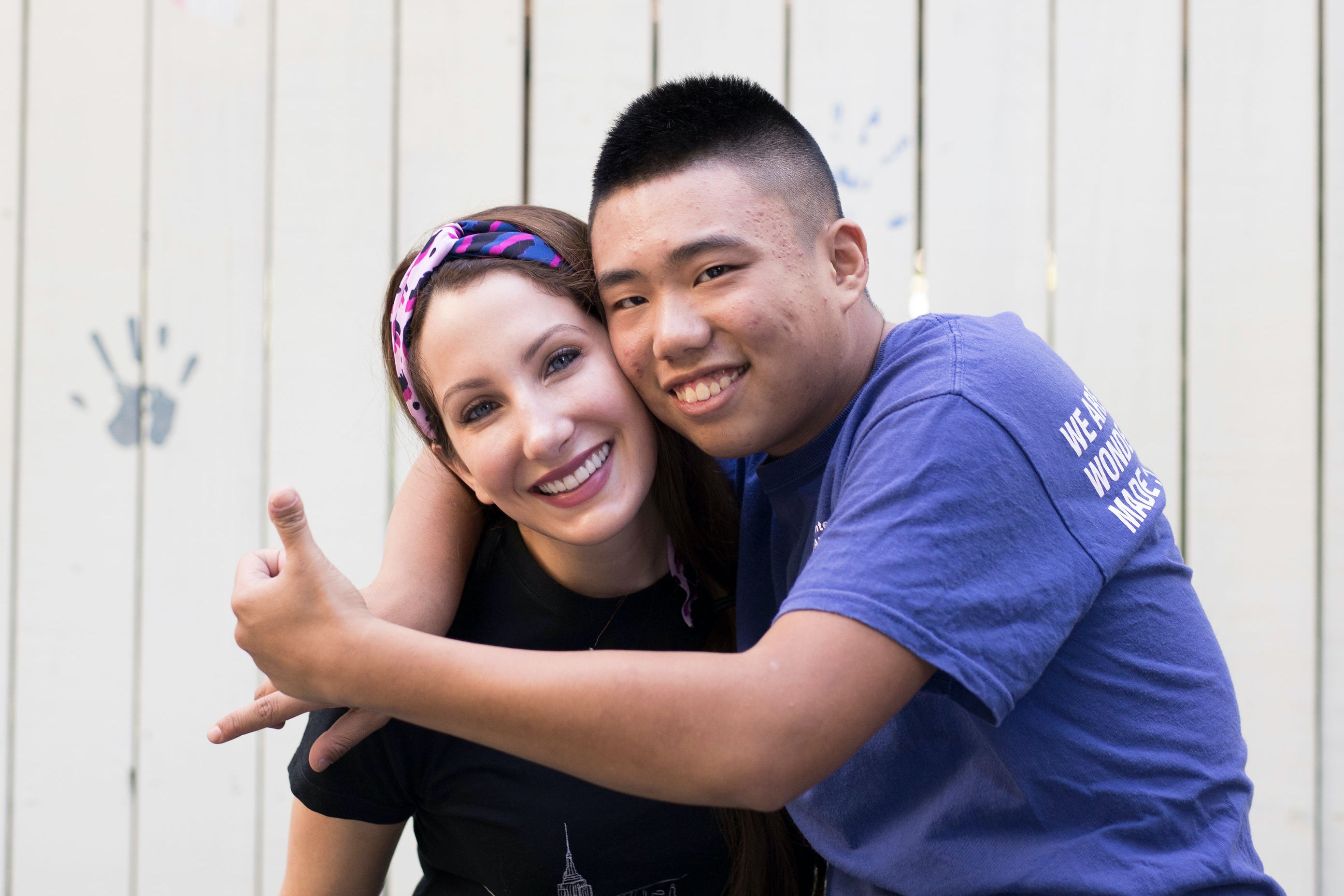 A woman is embraced by a young man who poses with thumbs up