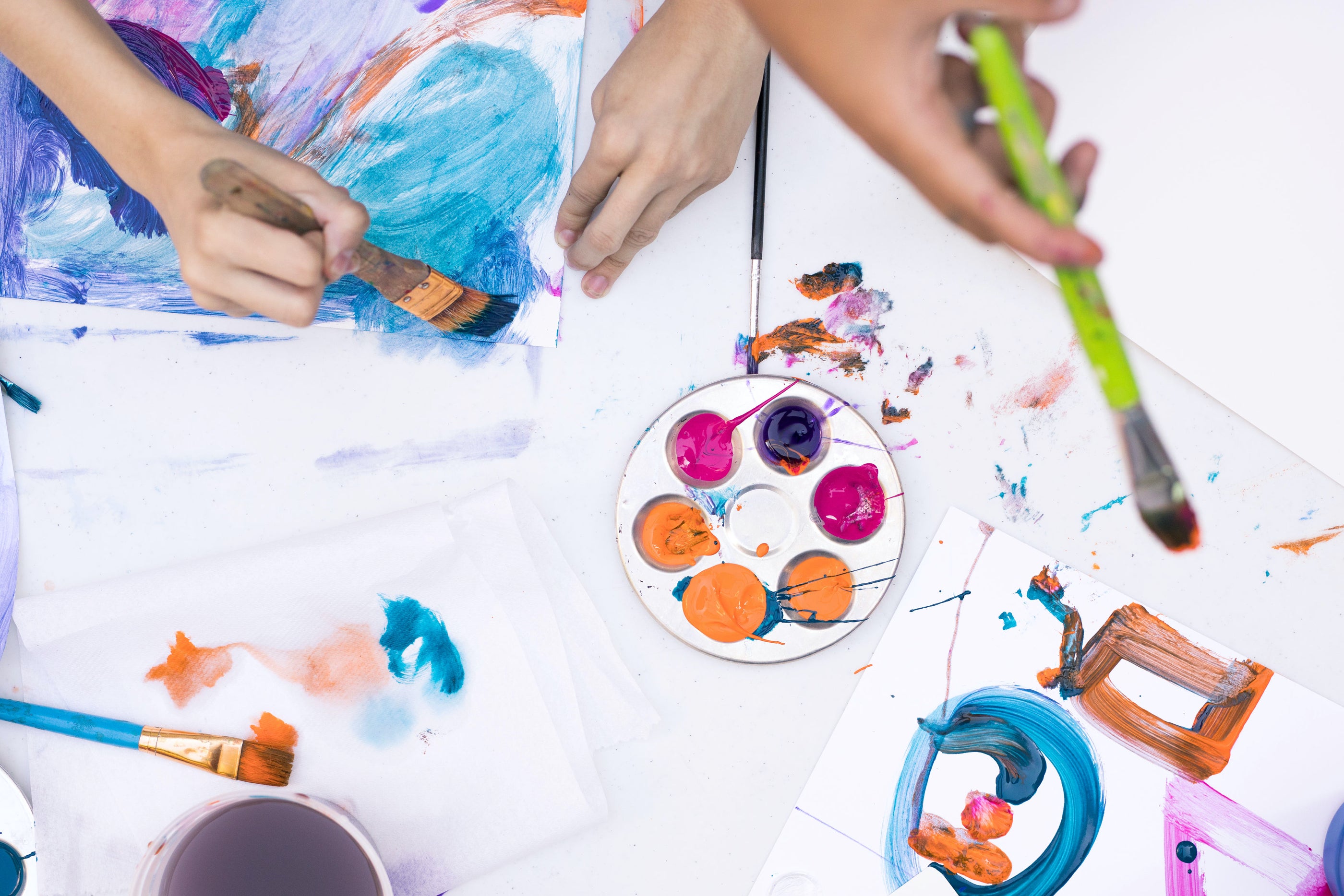 Top view of hands painting on a white table with watercolors