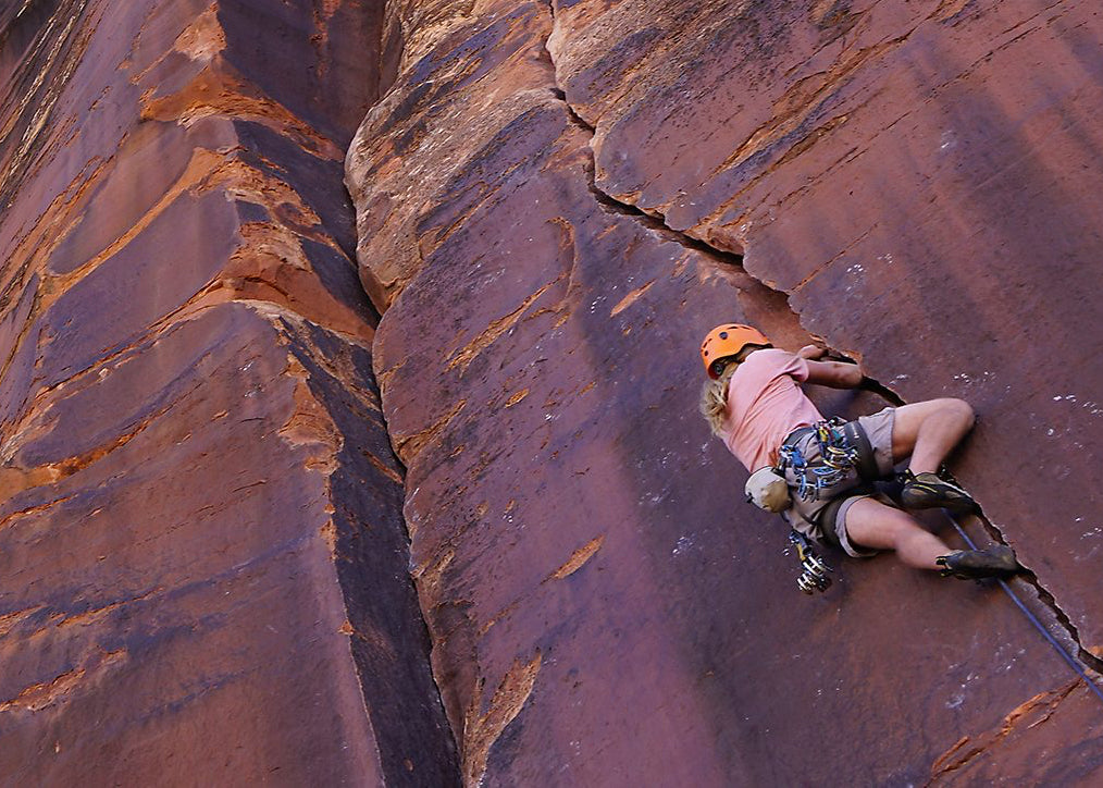 A woman climbs the face of a rock