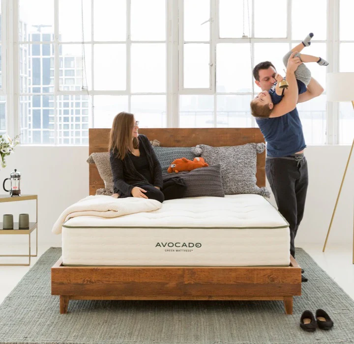 A family relaxes and plays on an Avocado mattress, showcasing a warm family moment.