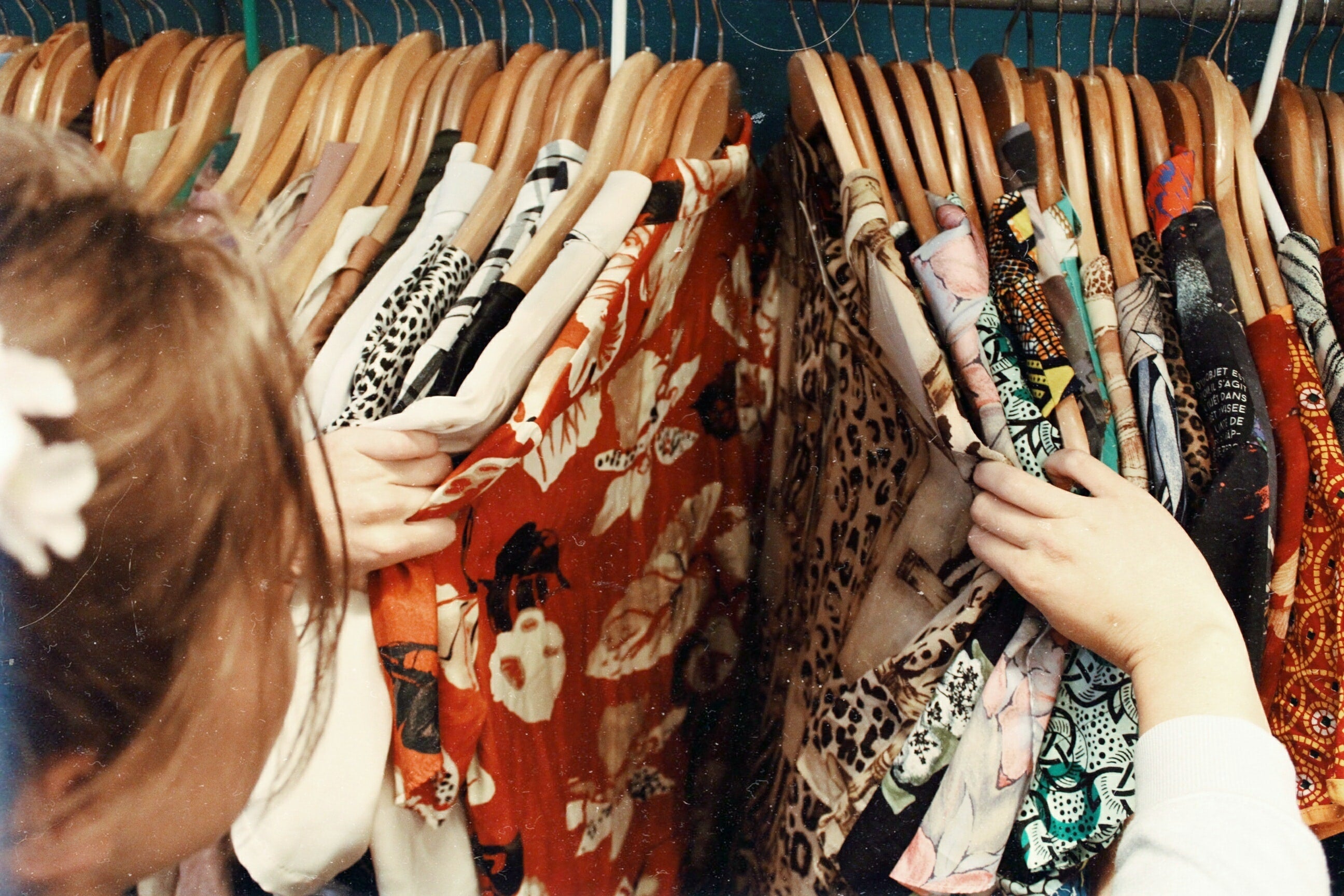 Shopper sorting through various shirts on a rack