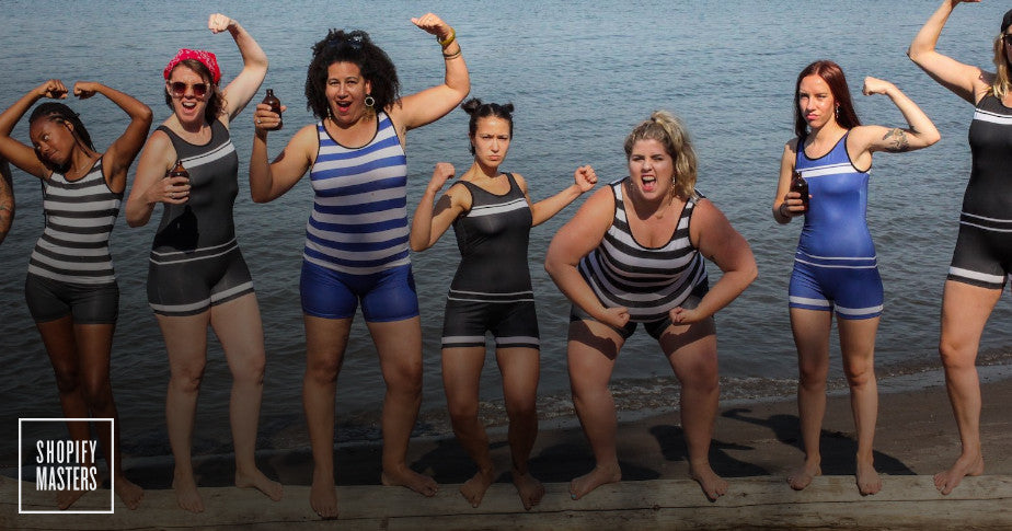 Seven models on a dock wearing Beefcake Swimwear.