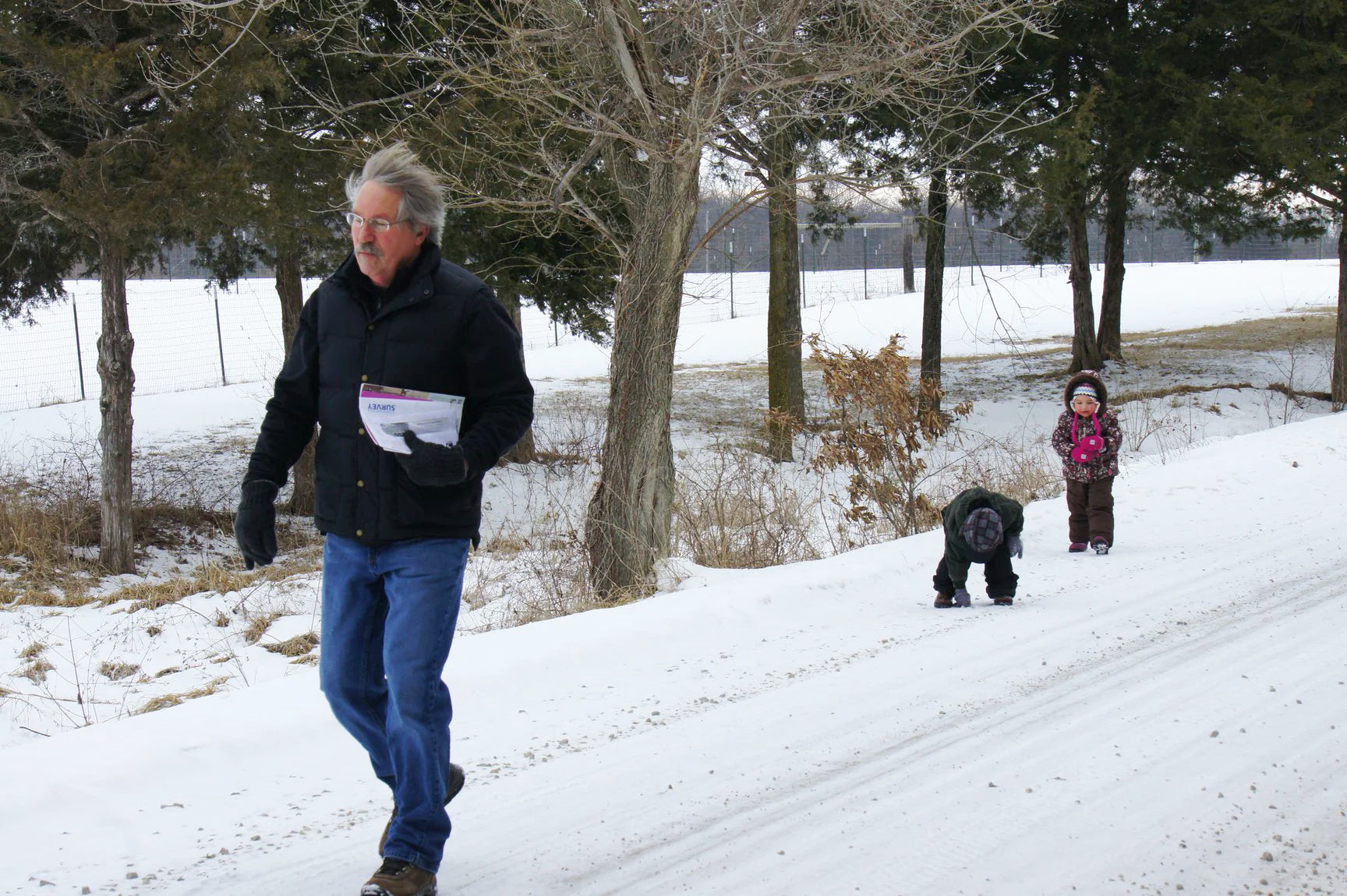 Bernie Rothrock walks down a snowy path with his grandchild and dog