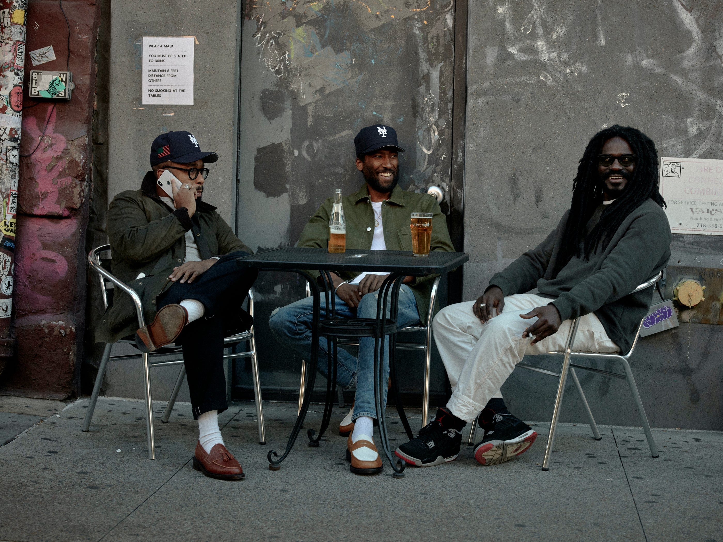 Three people have drinks at a table near a sidewalk cafe