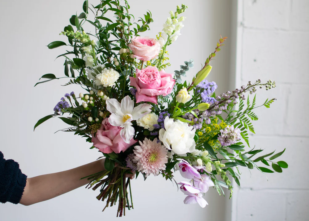 A hand holds a large bouquet of flowers