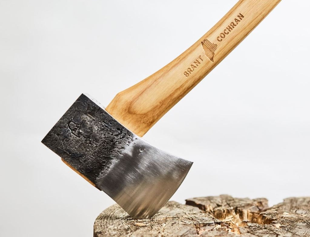 Wooden-handled axe sticking out of a log against a white background