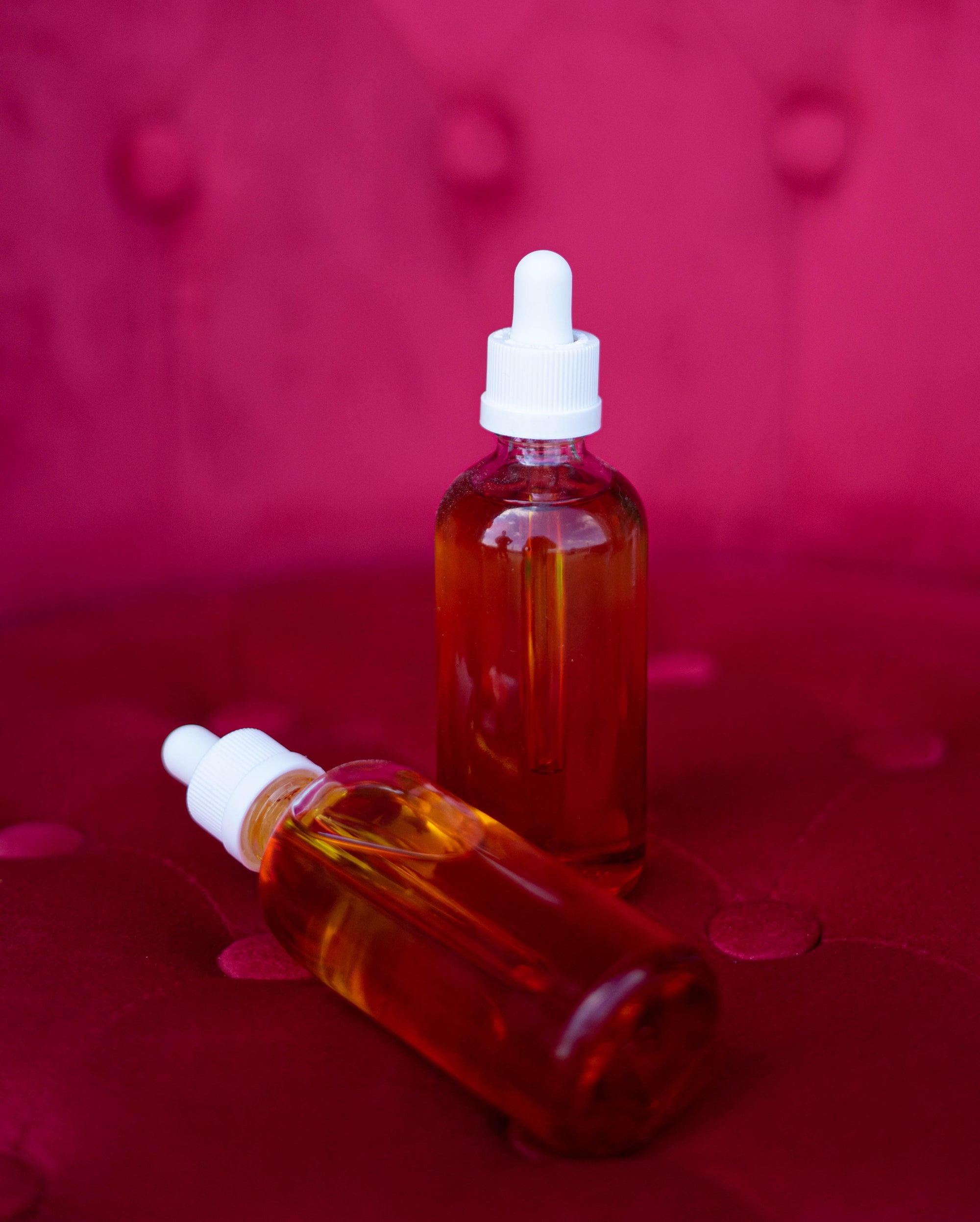 Bottles of skincare oil on a red velvet background