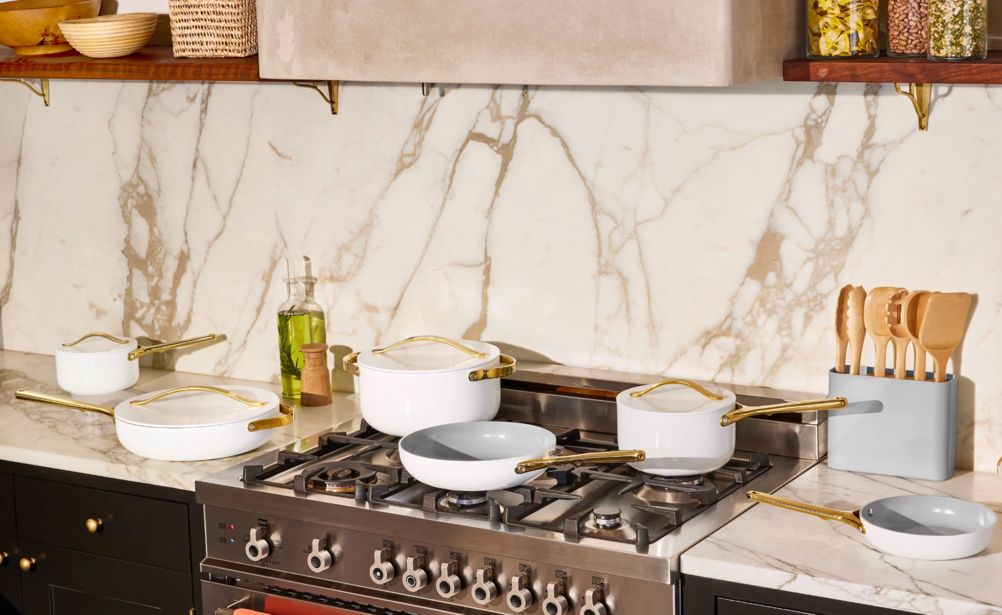 White and gray cookware on a stovetop in a modern kitchen with marble countertops.