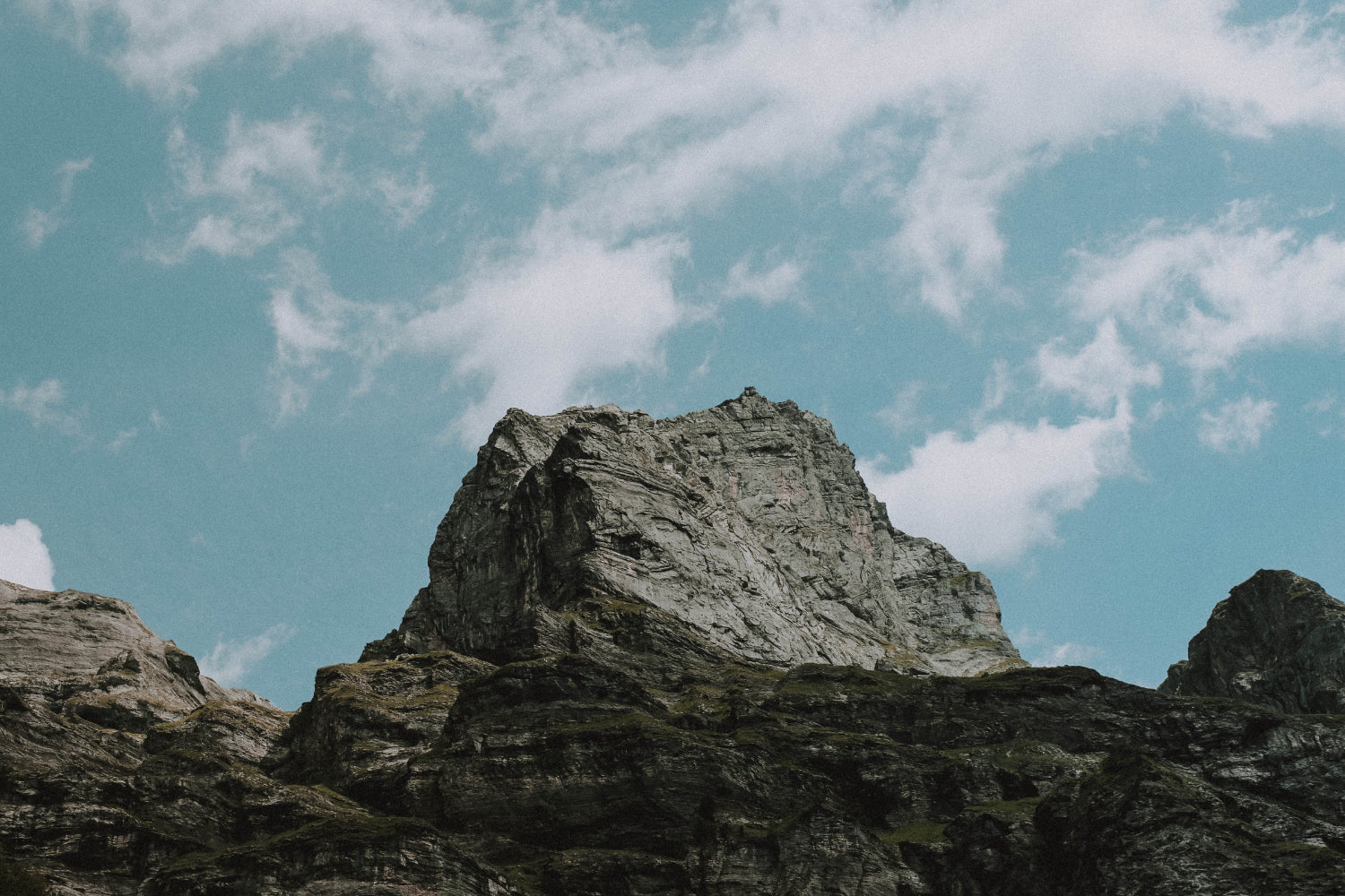 View of a mountain from afar set against a blue cloudy sky