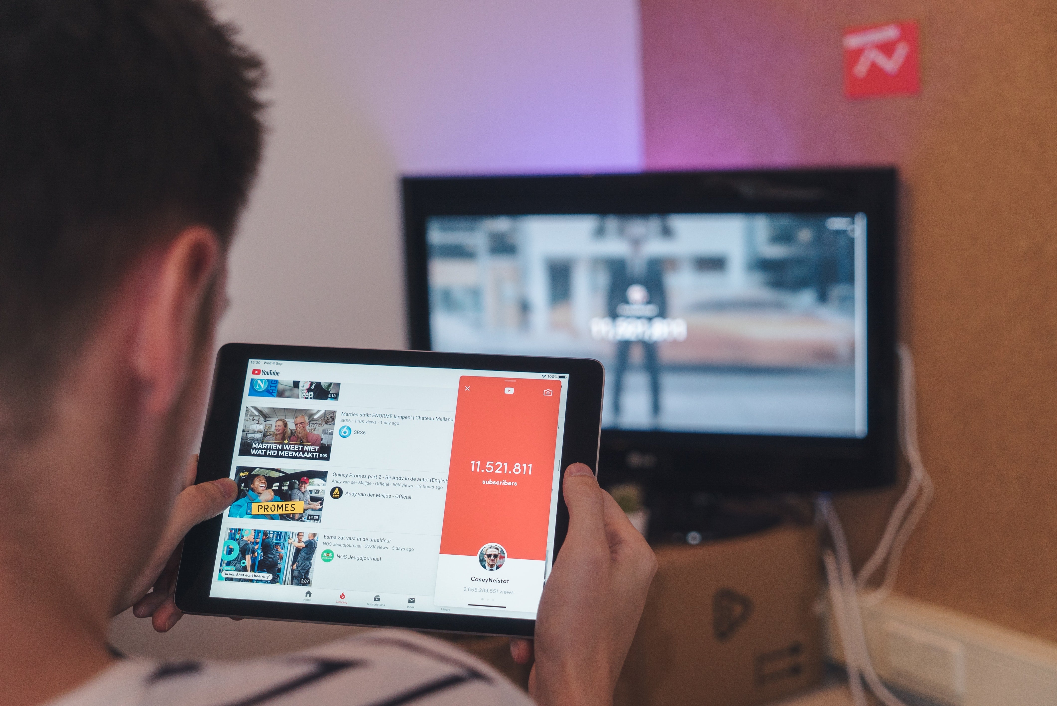 Man browsing YouTube on tablet in front of TV