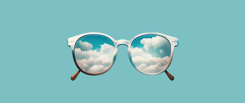 A pair of eyeglasses reflect a sky in each lens