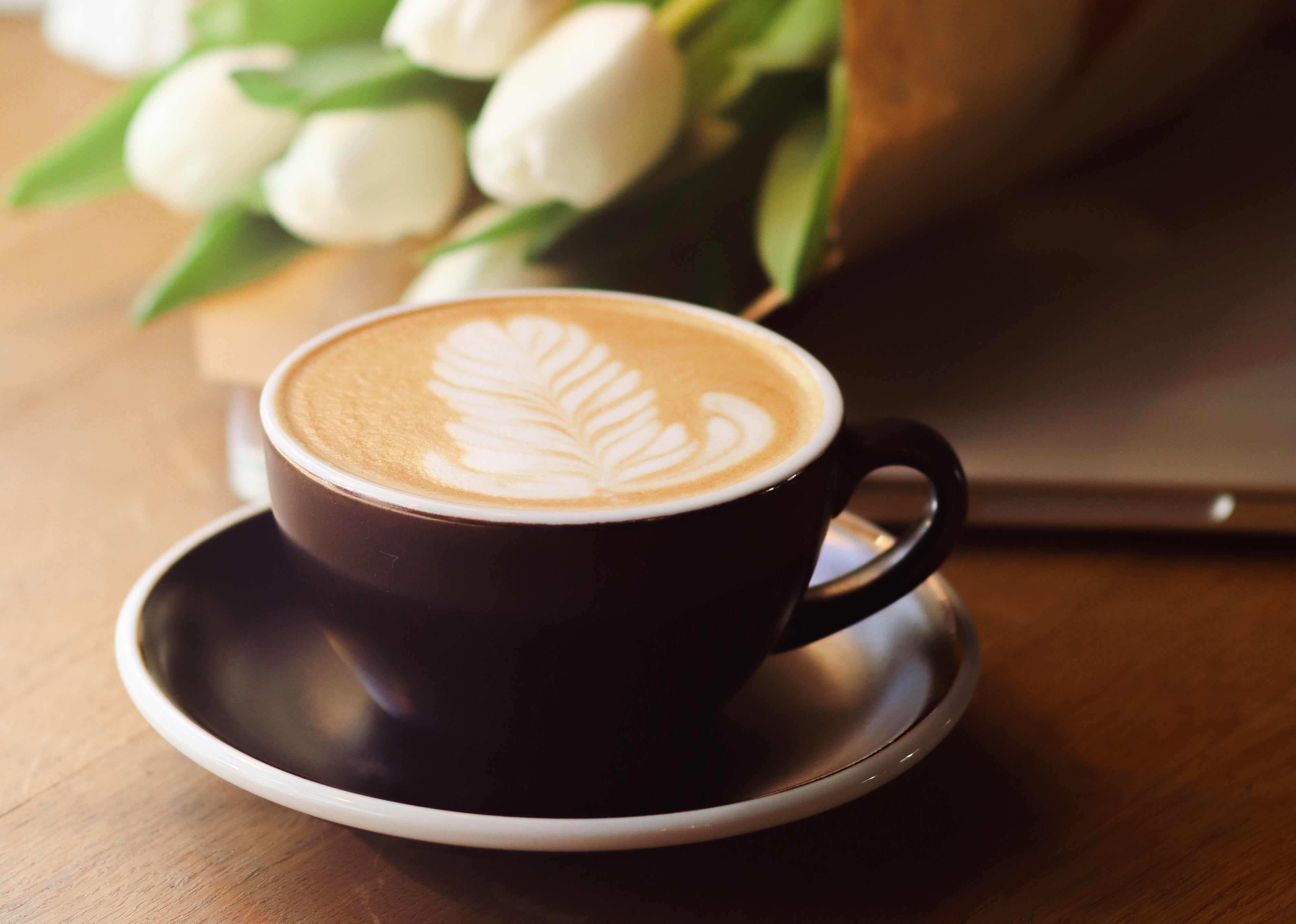 An image of a brown coffee cup and tulips in the background. 