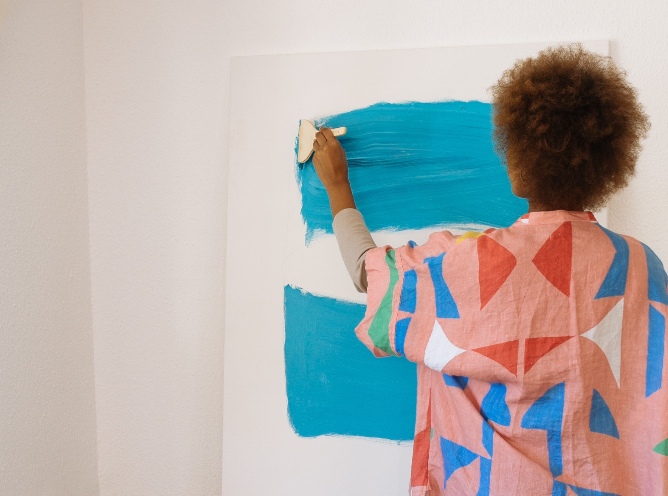 Person paints an abstract design on a large canvas.