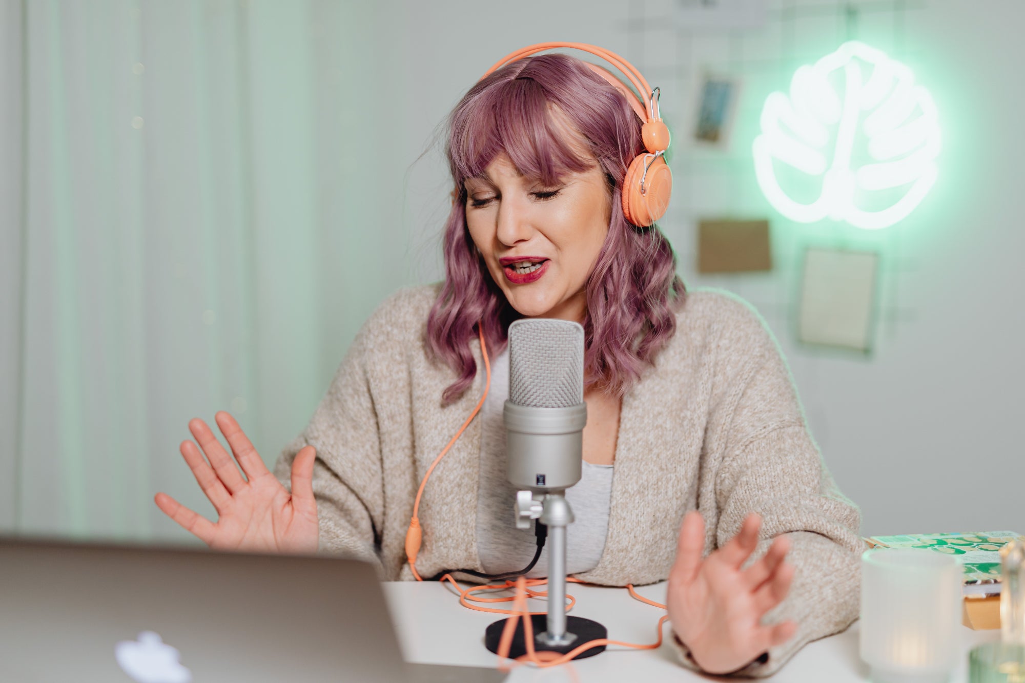 Person wearing headphones speaks into a mic while recording a podcast