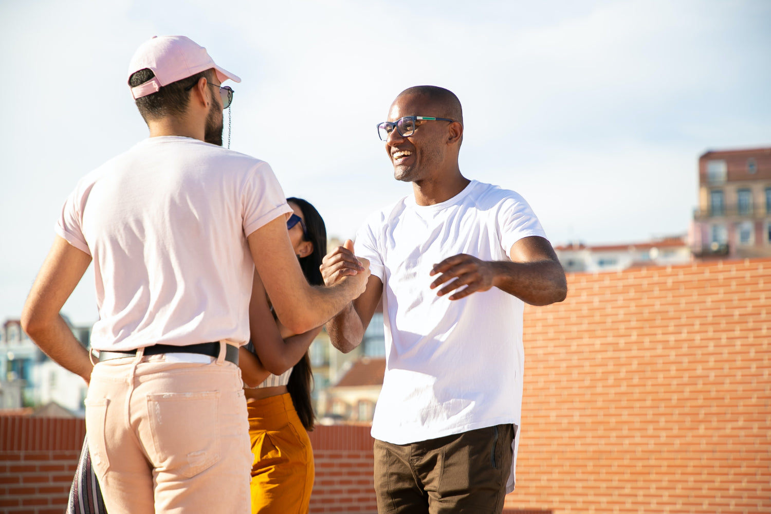 Two people shake hands on a rooftop patio