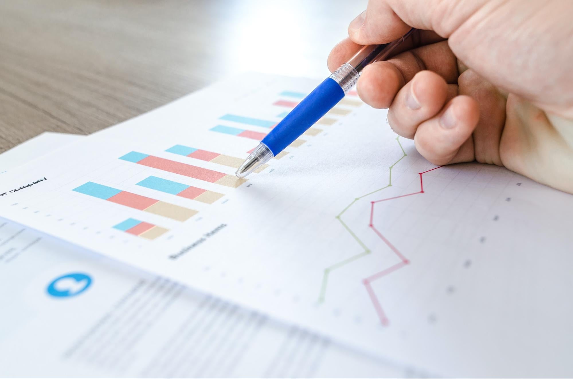 A hand holding a blue pen above some business documents