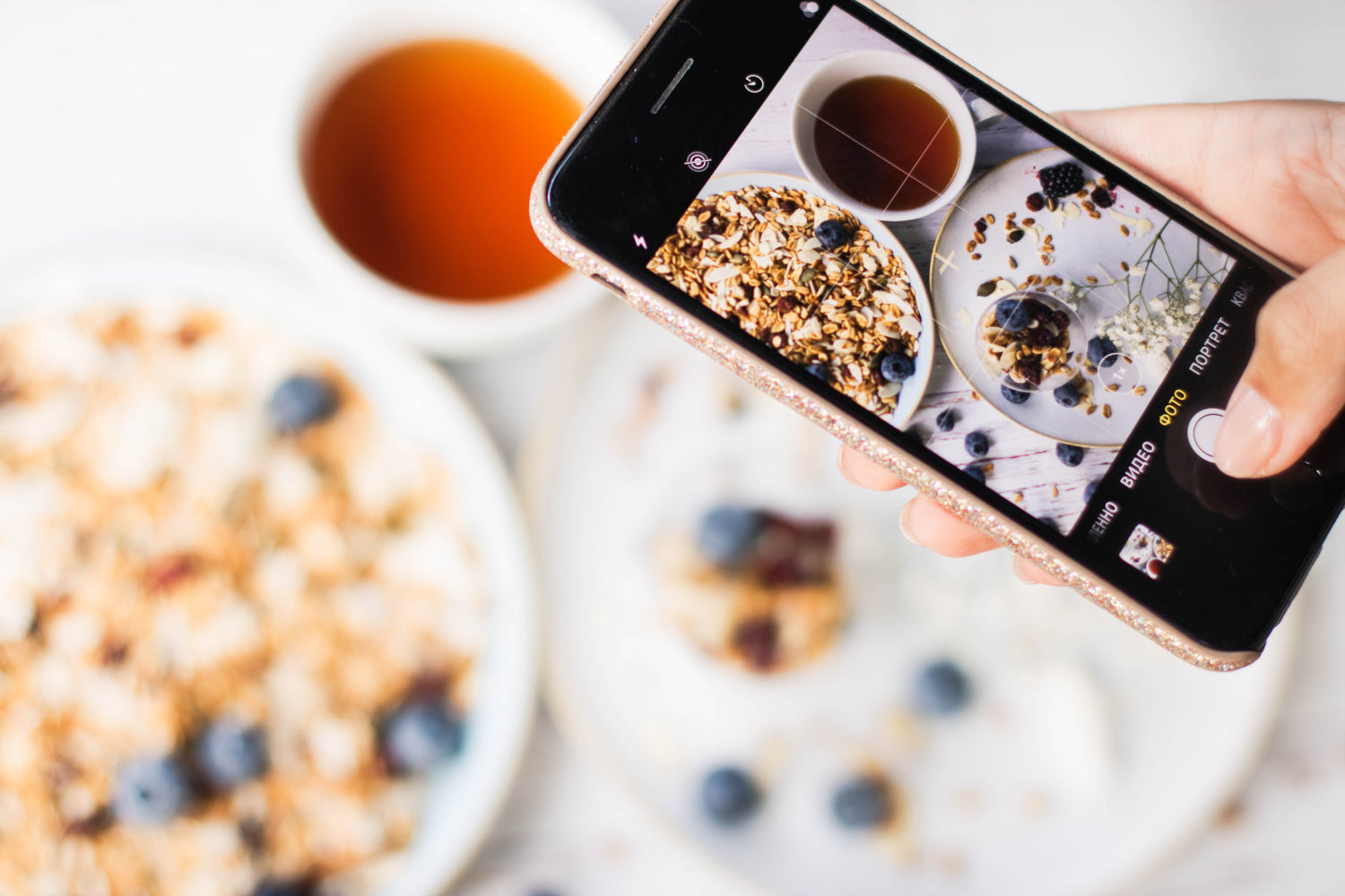 Hand holding a mobile phone shoots a photo of food