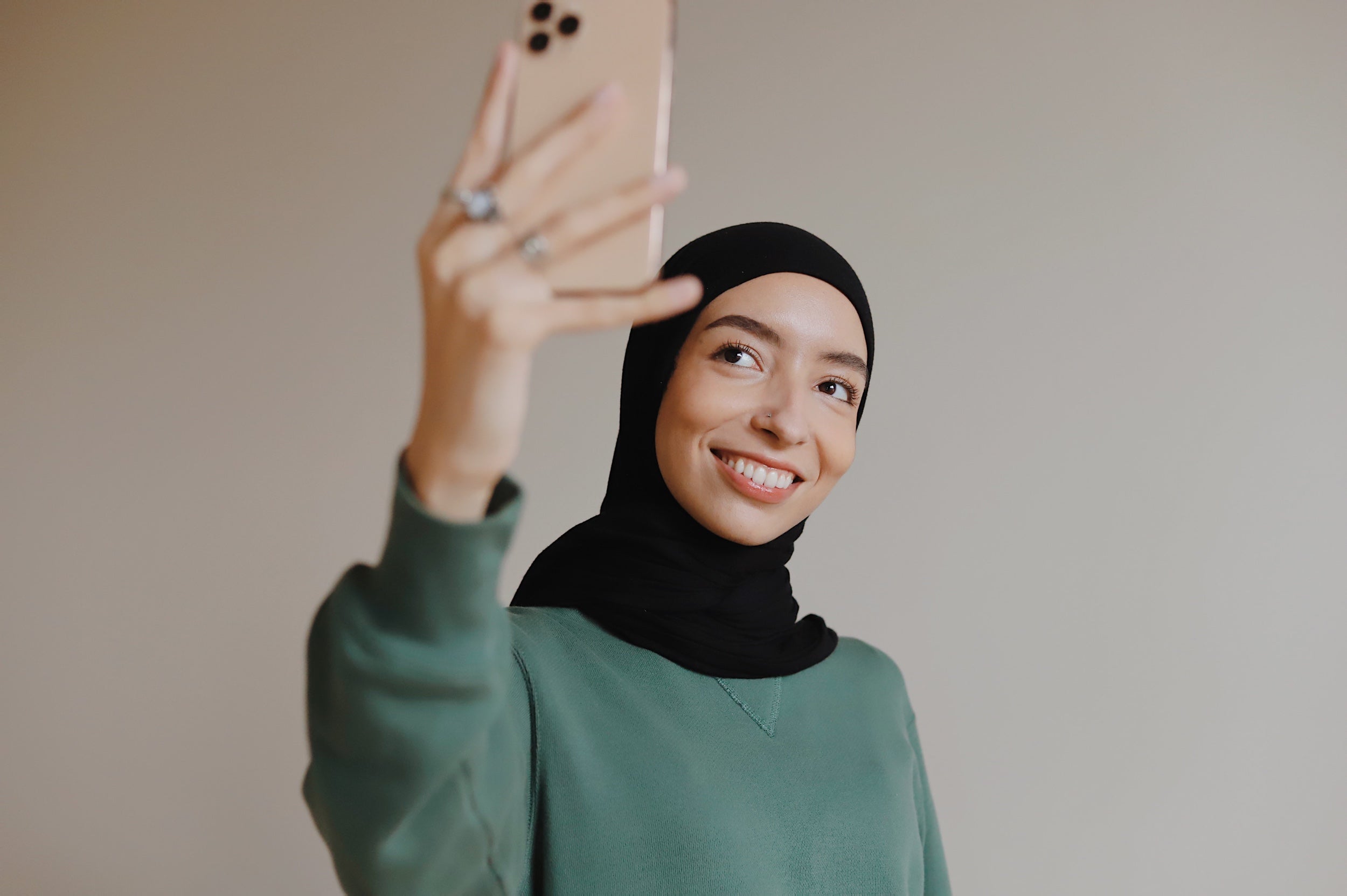 Portrait of a person wearing a hijab taking a selfie with a mobile phone