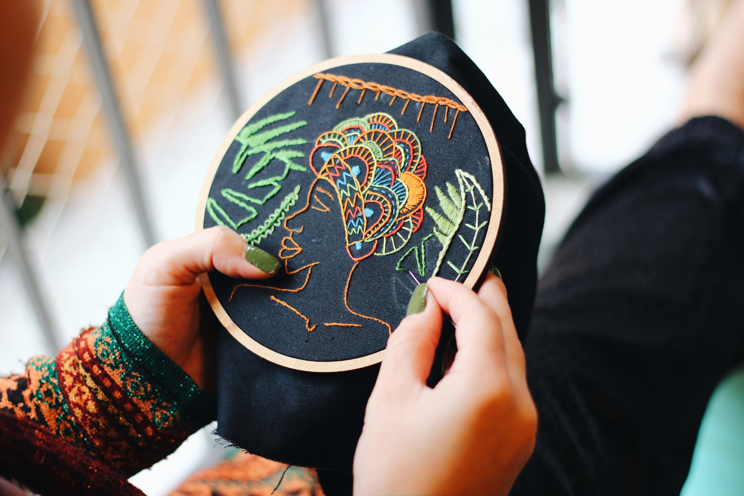 Close up of hands working on textile crafts in an embroidery hoop