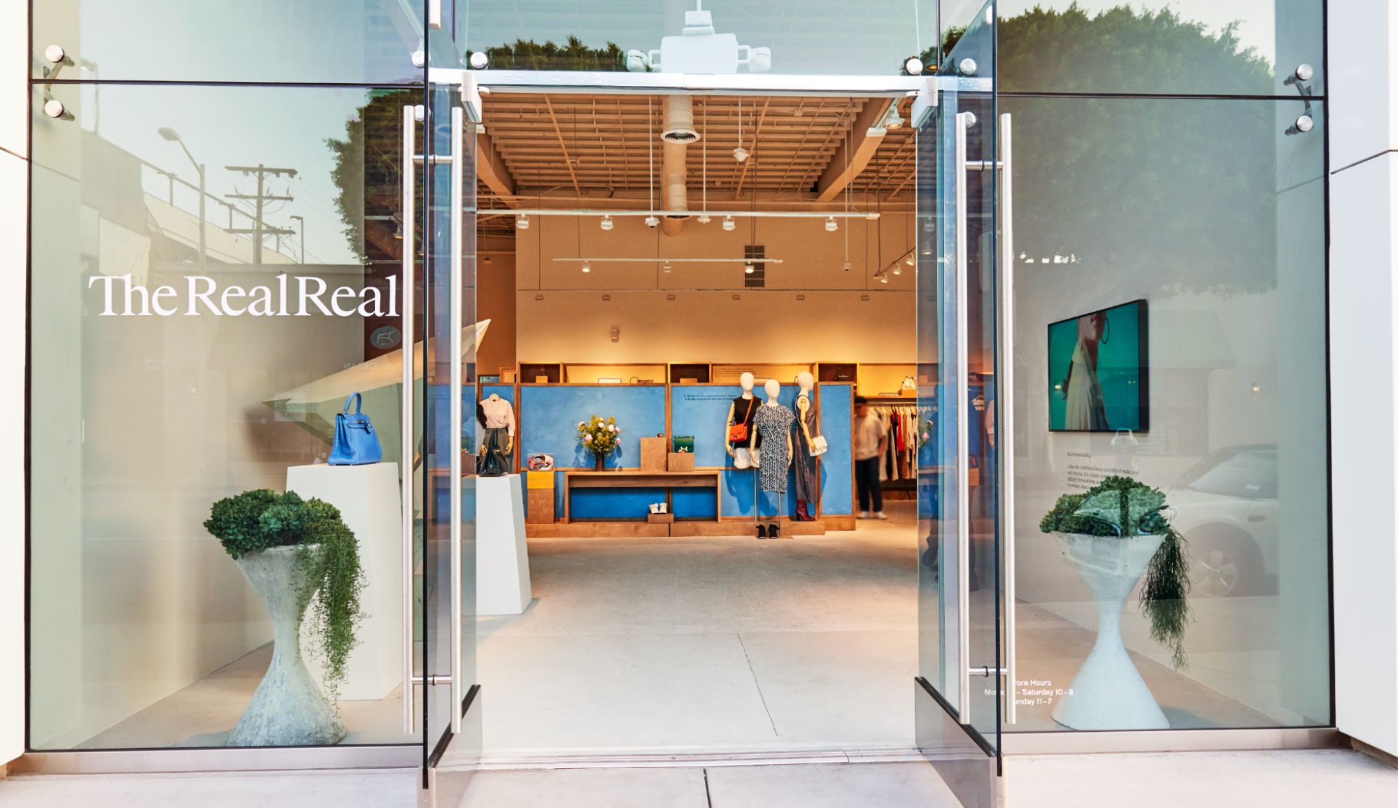 The RealReal retail store entrance with mannequins and luxury items inside