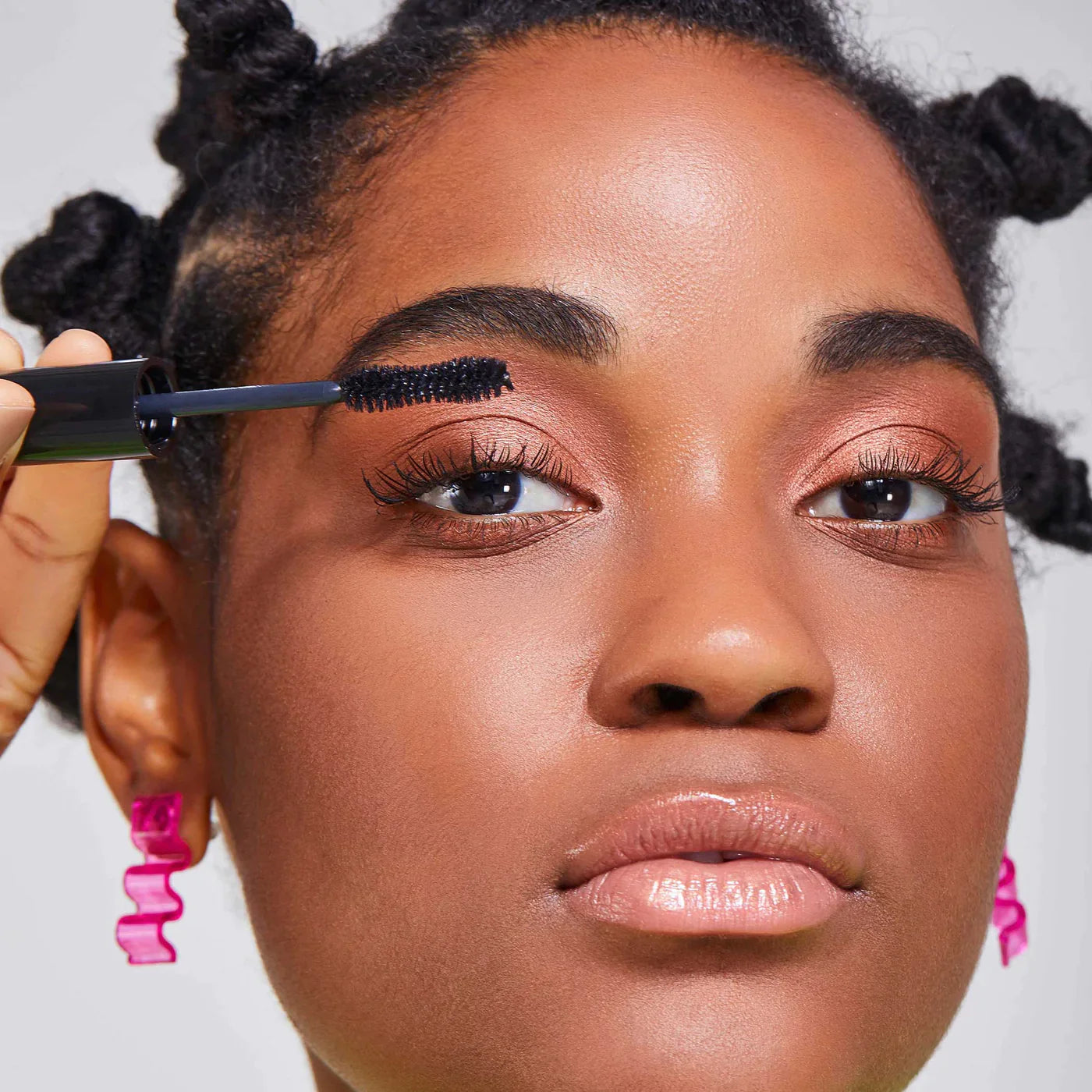 A close up portrait of a woman applying mascara