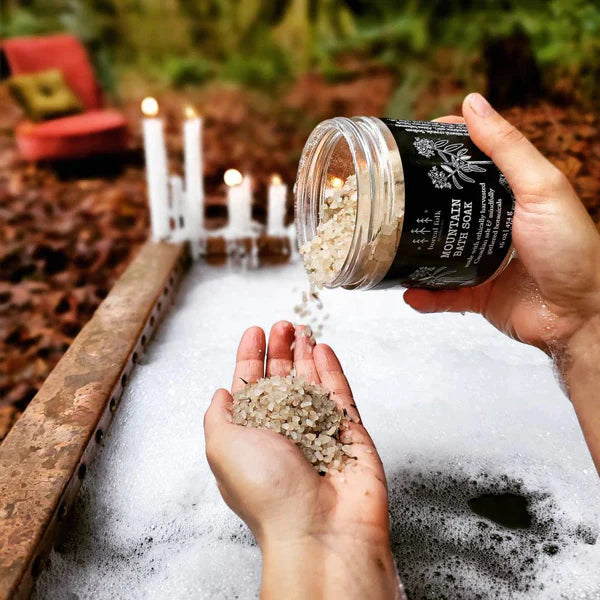 Bath salts pouring into a hand with a bath in the background