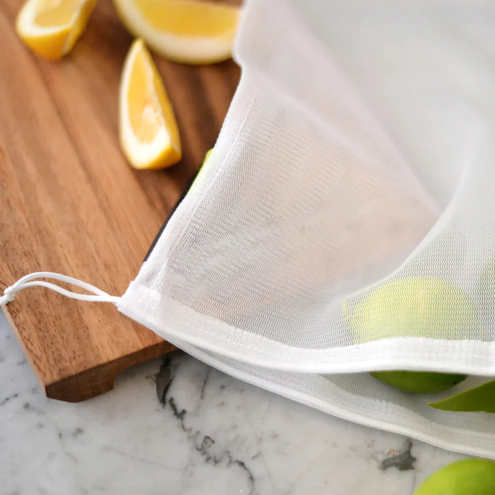 Mesh bag for fruits and vegetables sits on a cutting board with fruit