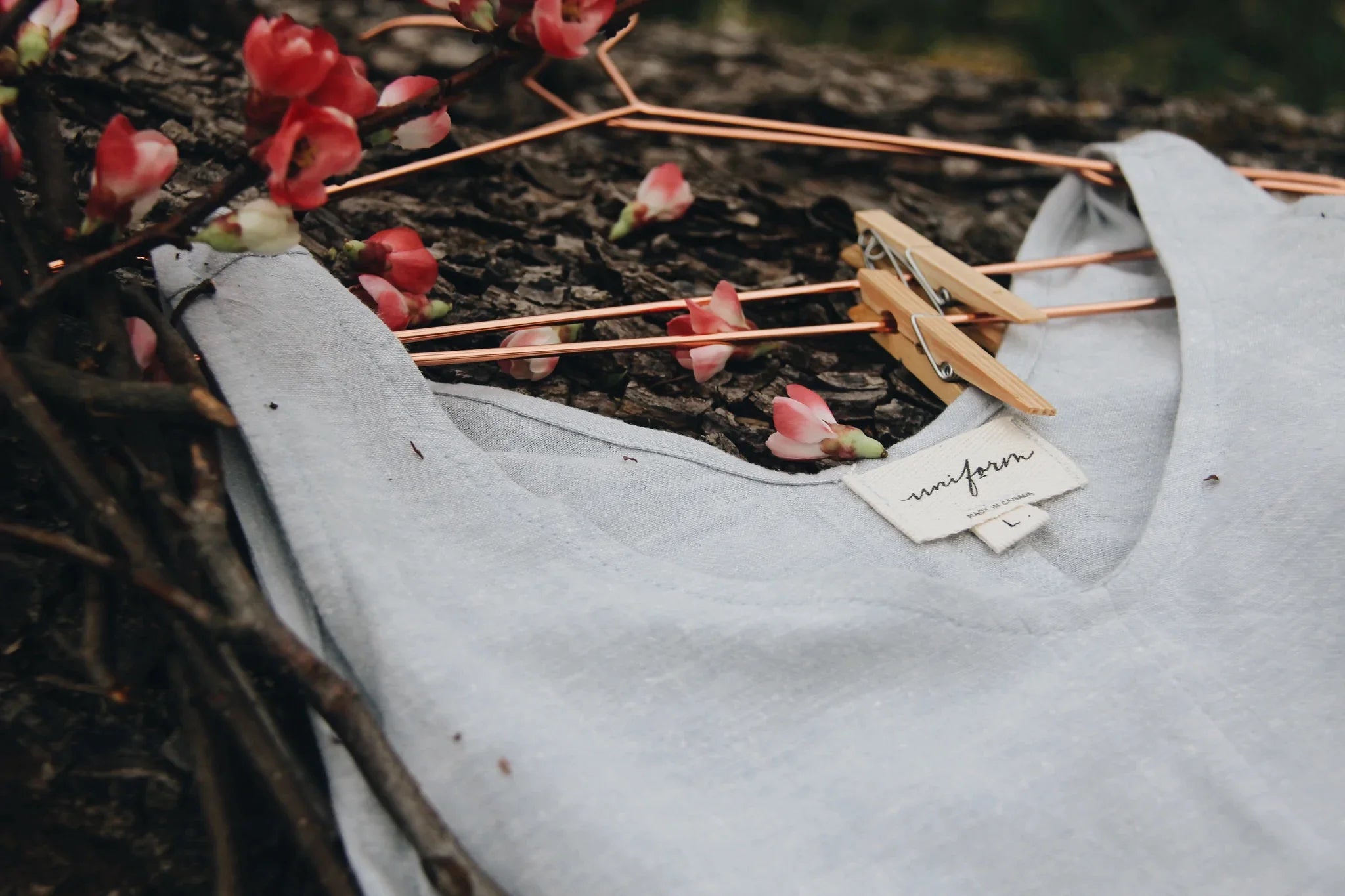 A linen top on a hanger lays on a natural grass surface