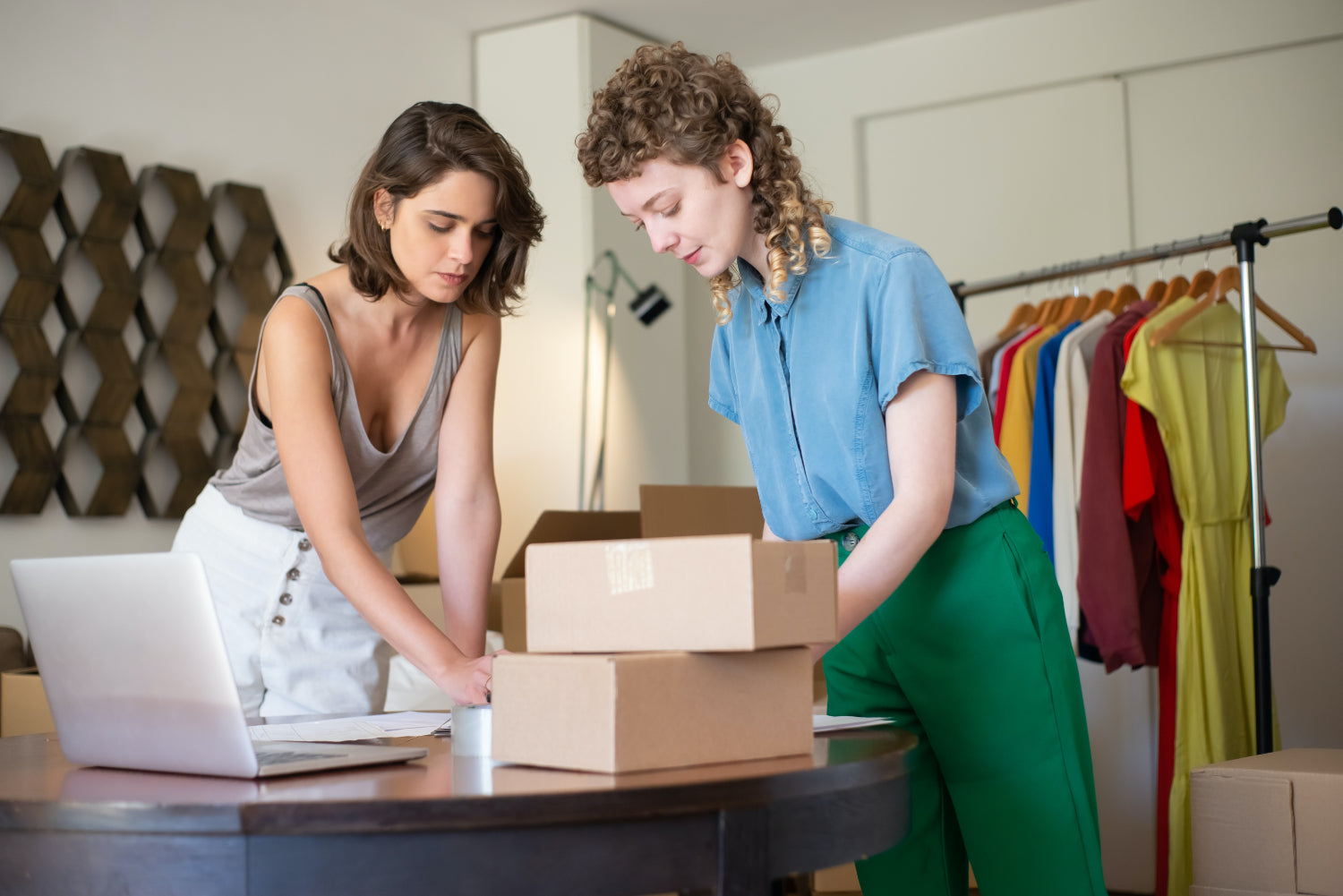 Two women pack a box for shipping