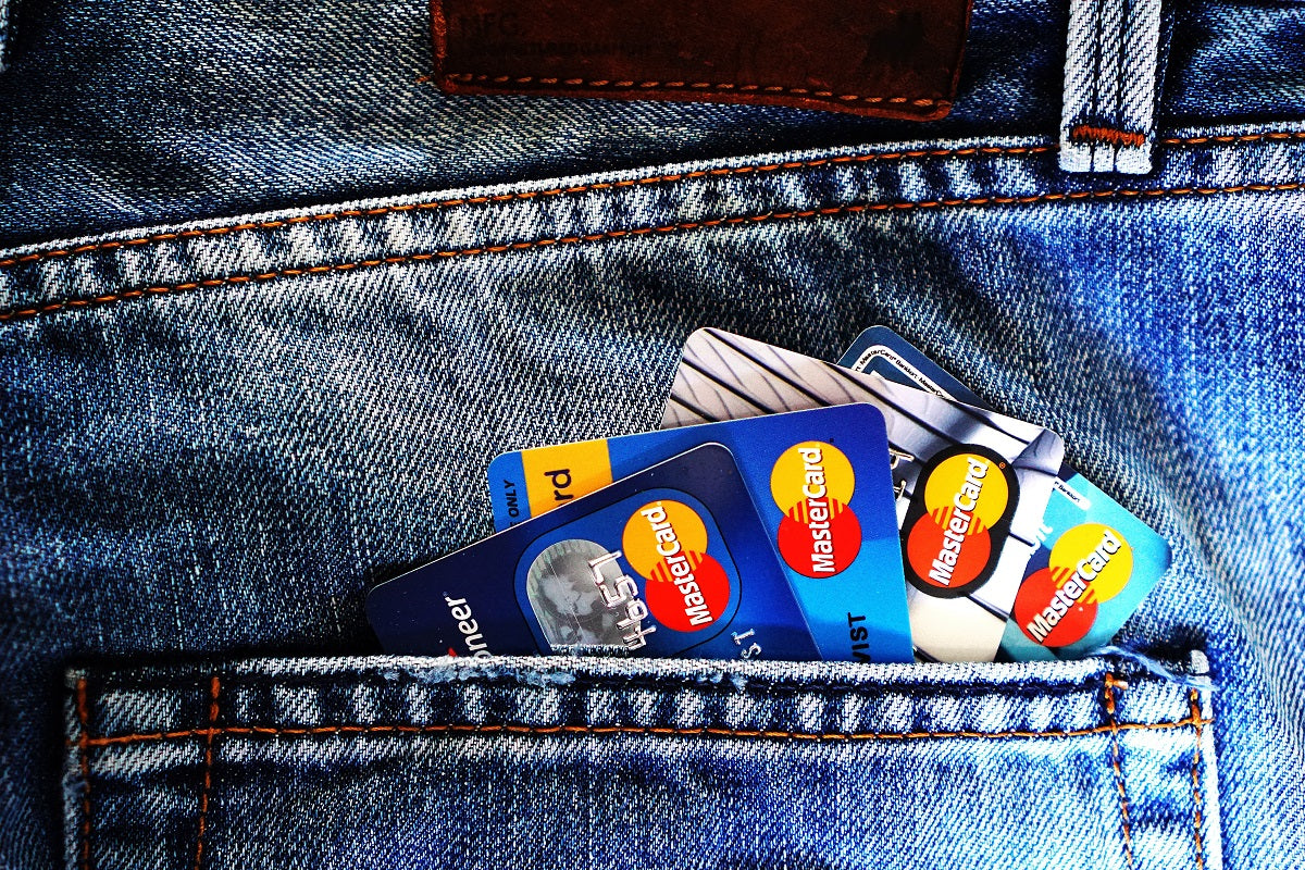 Four Mastercard credit cards sticking out of the back pocket of a pair of jeans