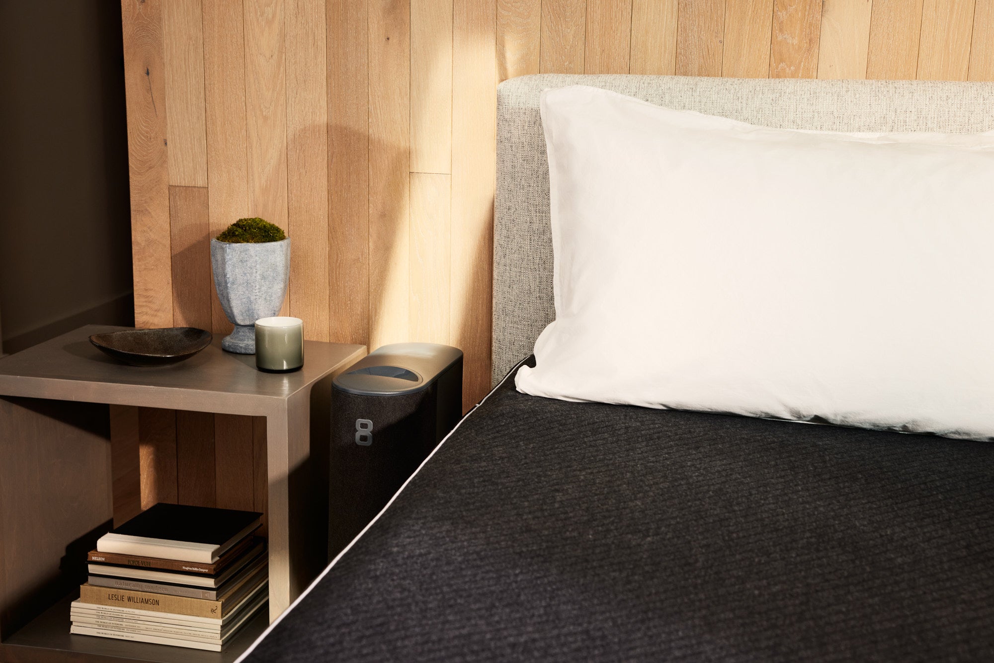 The Eight Sleep Pod Pro mattress and Hub is pictured next to an open concept nightstand in a bedroom.