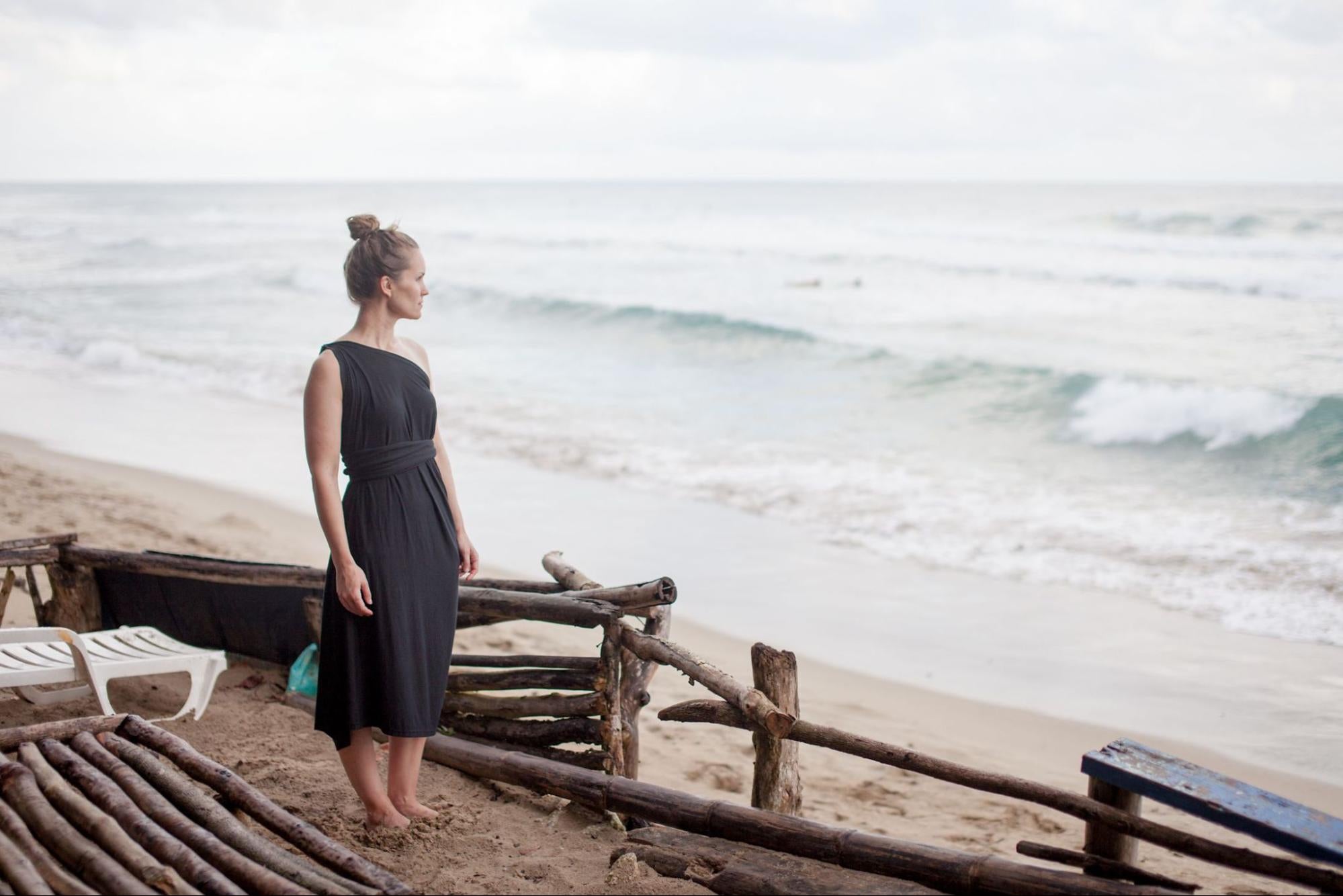 A model standing on a beach wearing a dress by Encircled. 