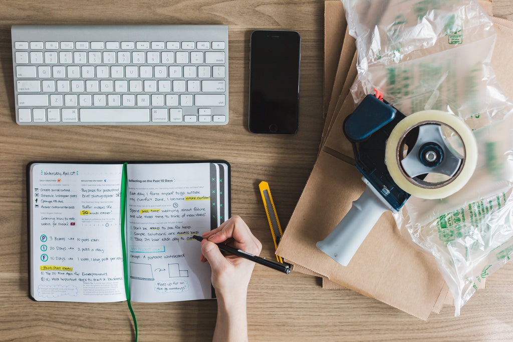 Entrepreneur tabletop planning with keyboard, notebook, and tape.