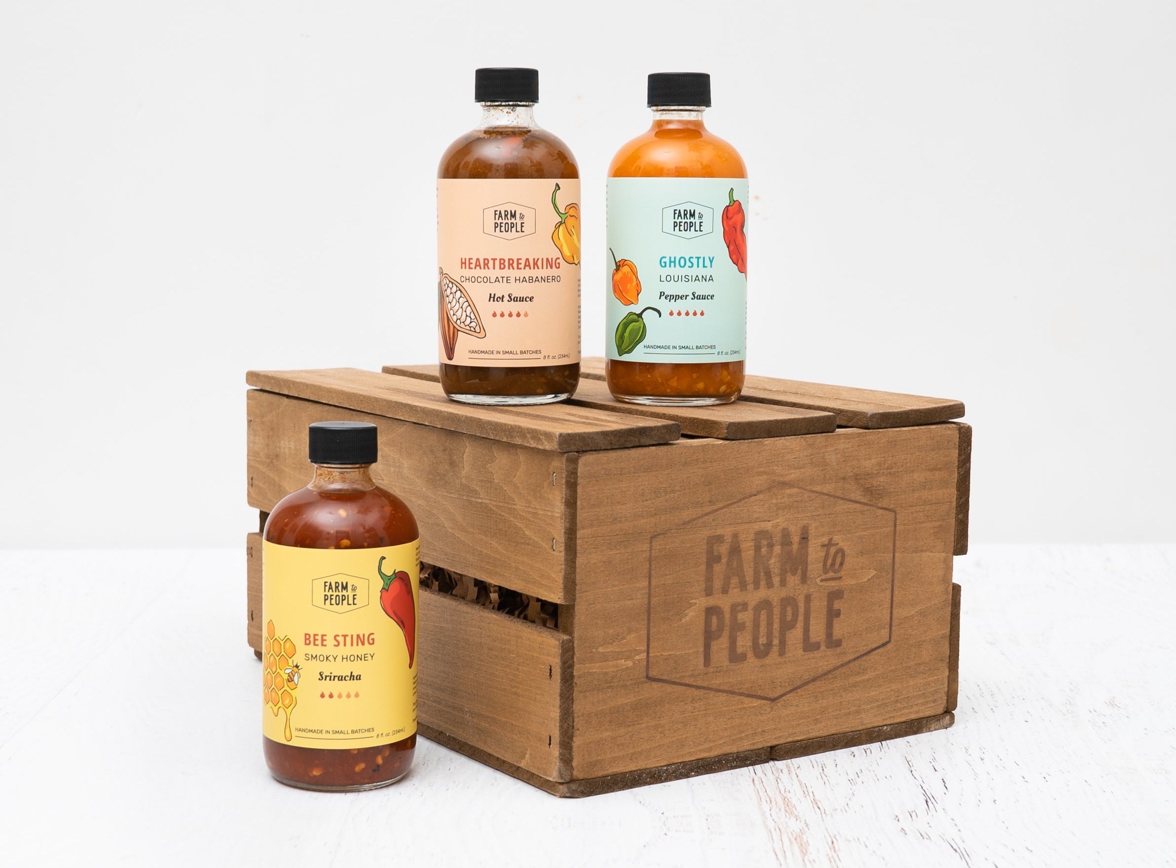 farm to People gift set featuring 3 bottles of hot sauce styled on a wooden crate