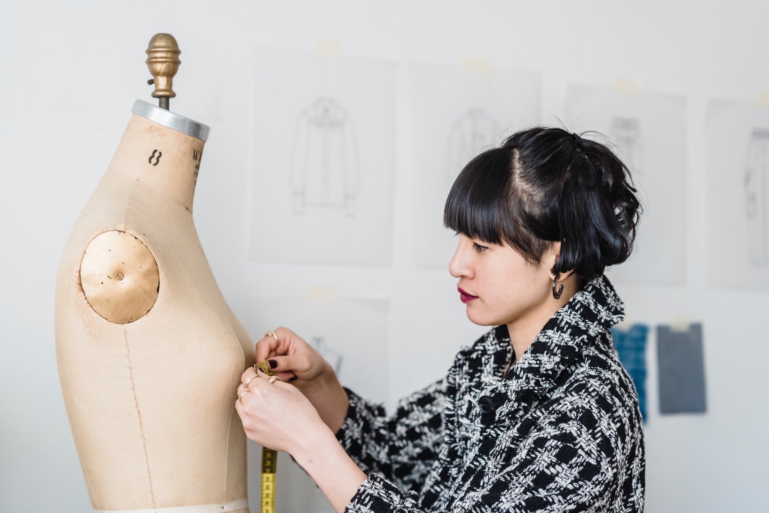 A person measures a dressmaker's form