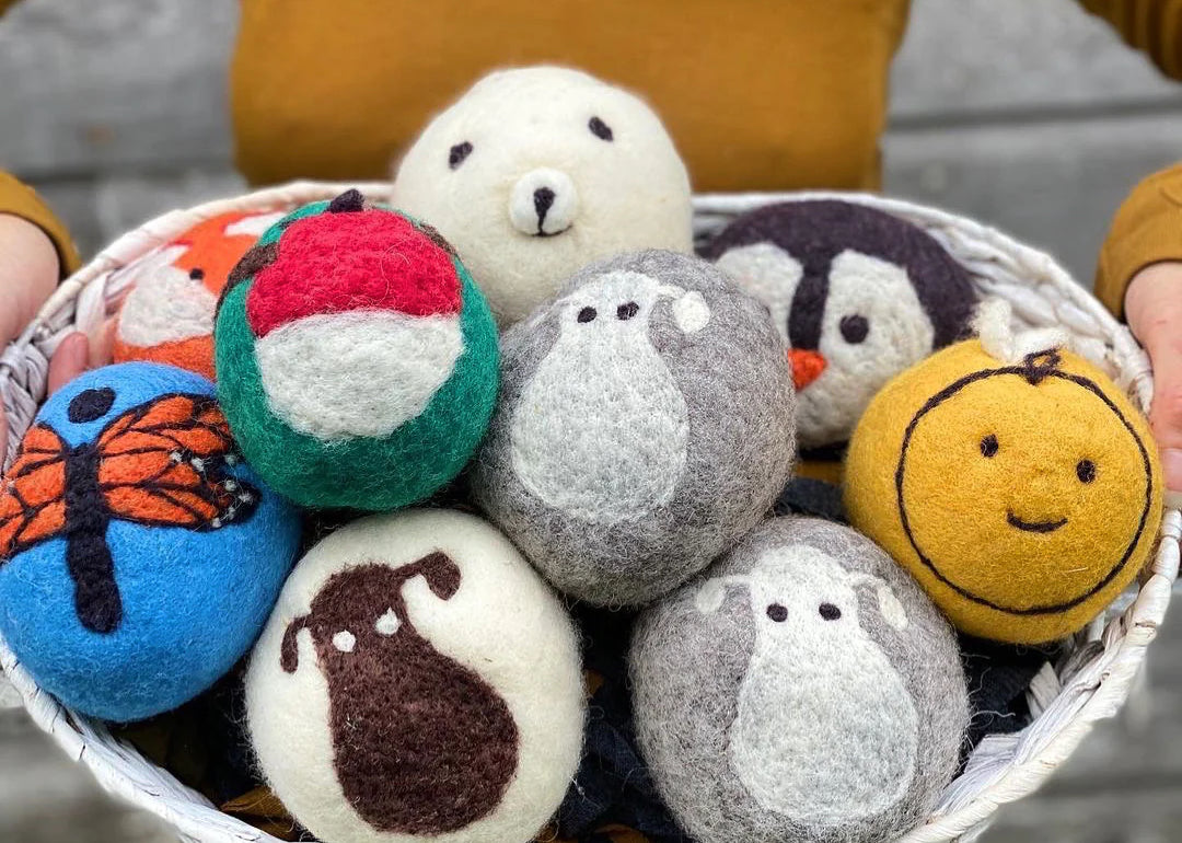 A person holds a basket of felted dryer balls, an easy craft to make and sell