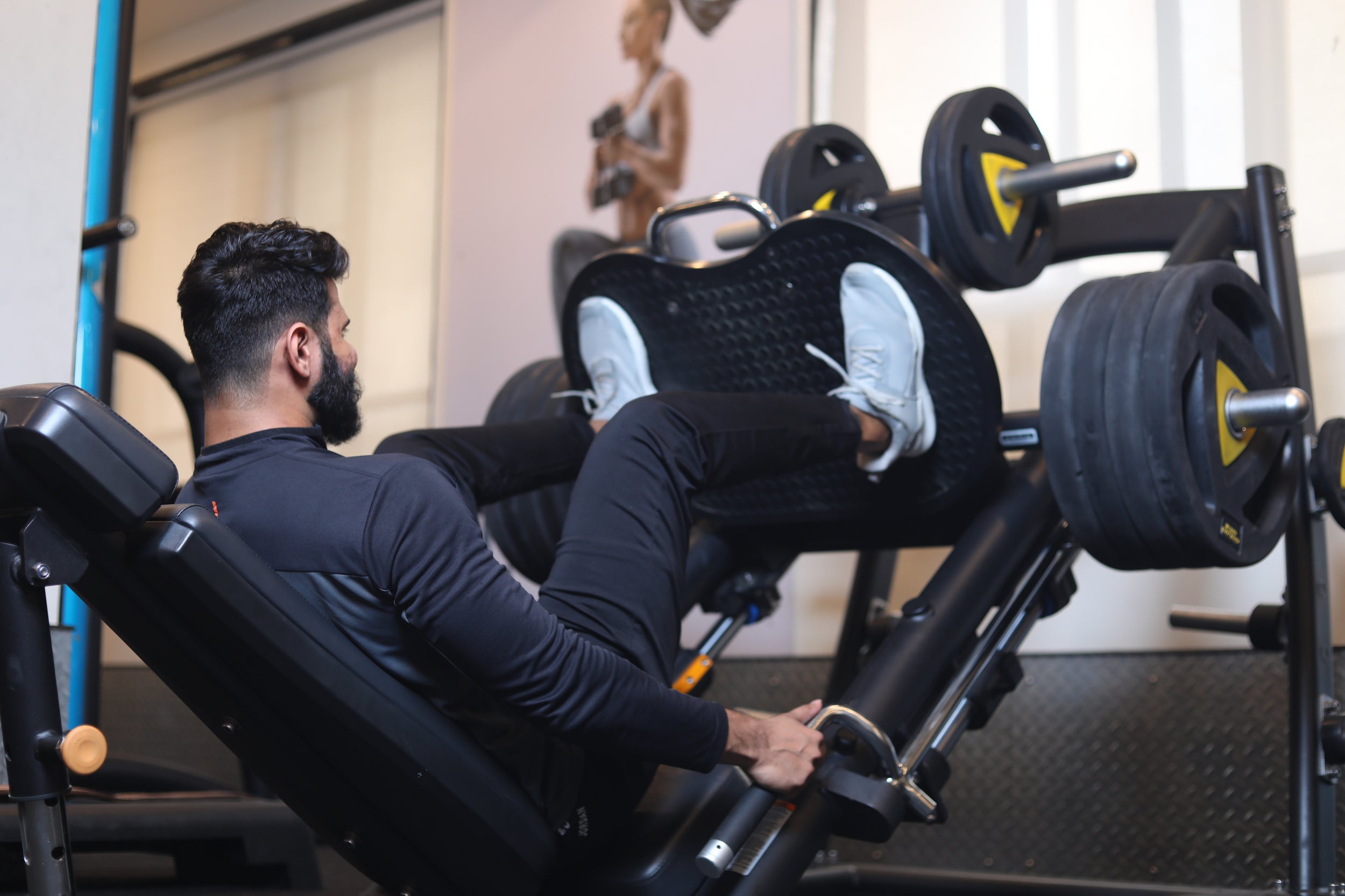 Person uses a weight lifting machine to do a thigh press 