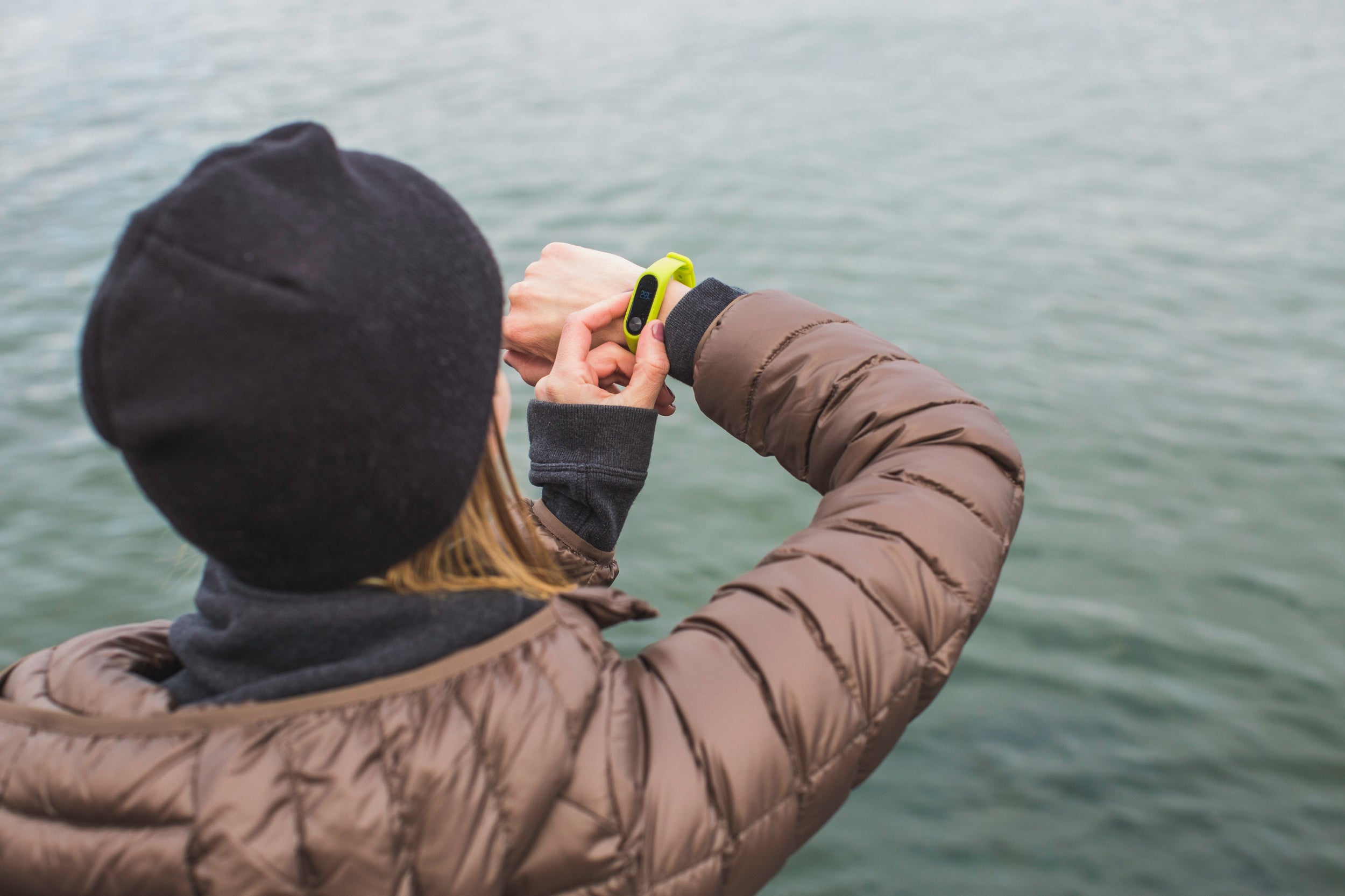 Person looks across a body of water and adjusts their smart watch fitness tracker