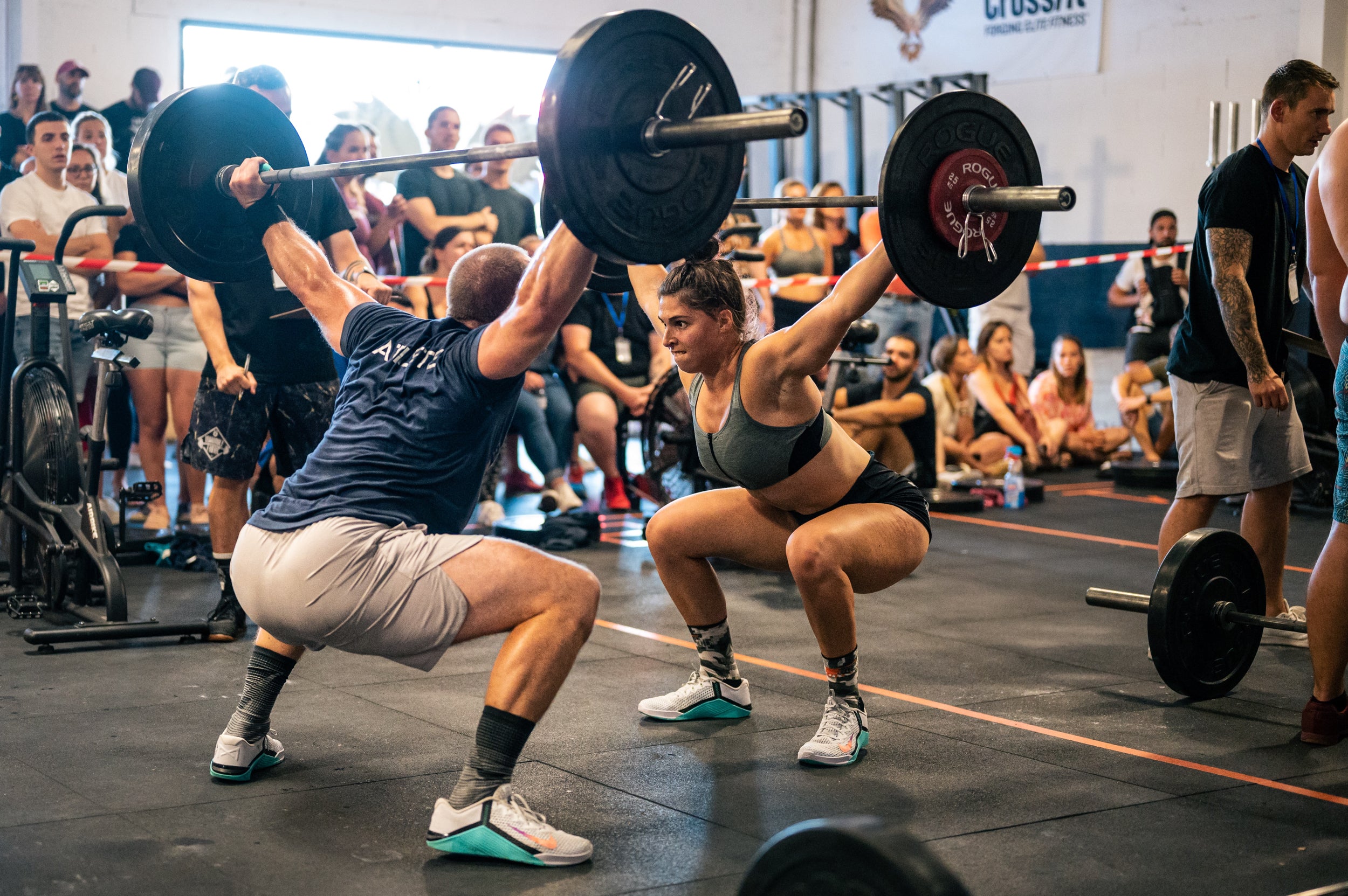 Two people compete in a weightlifting competition in front of an audience