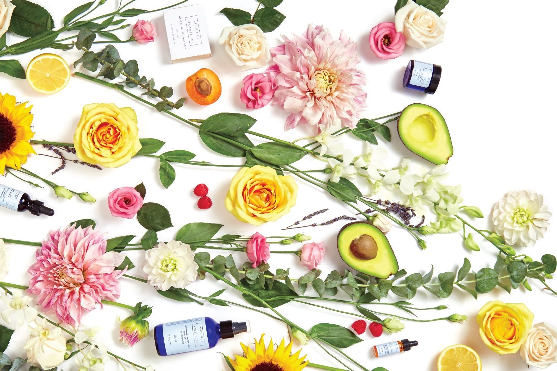 A flat lay of Province Apothecary products along with fresh flowers and other ingredients. 