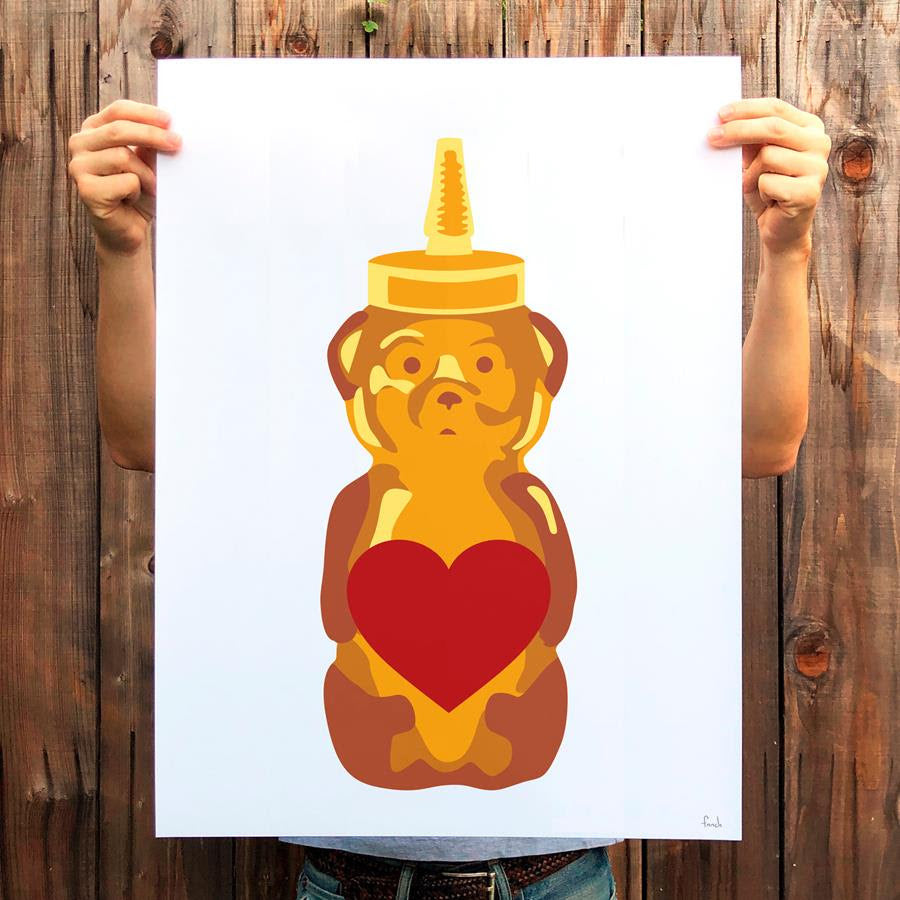 A person holds a print of a Fnnch honey bear holding a heart