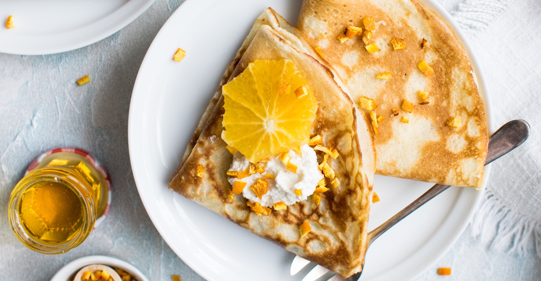 Image of a crepe with oranges and cream on top