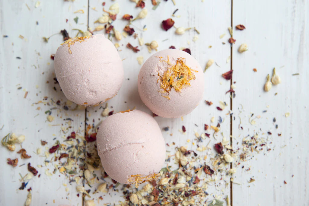 Three bath bombs grouped on a rustic surface with dried herbs